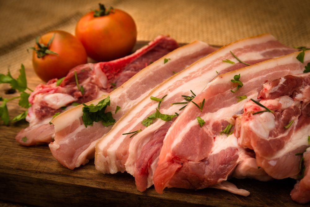 Raw Pork Chops And Tomatoes On A Wooden Cutting Board — McGrath Meats In Taree, NSW