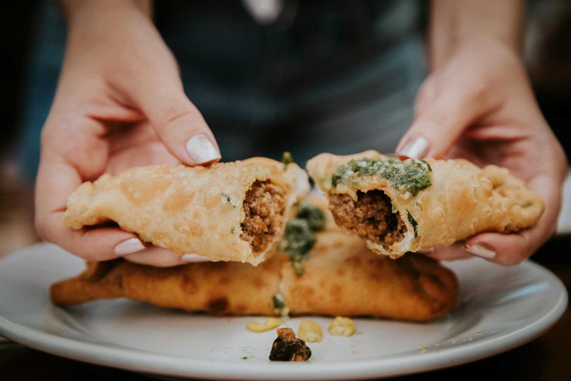 A person is taking a bite out of a pastry on a plate. — McGrath Meats In Taree, NSW