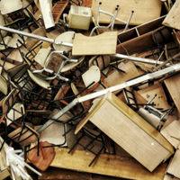 Pile of broken wooden and metal chair parts scattered in a workshop or scrapyard.