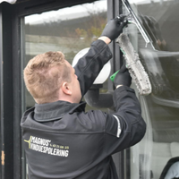 Worker in black jacket installing or cleaning window film on a glass door.