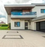 Modern two-story house with a large paved driveway and a garage under a cloudy sky