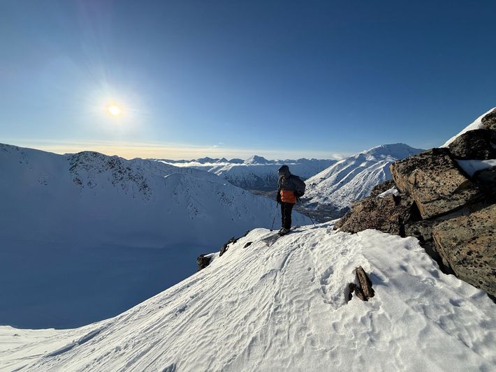 Mountain trail overlooking a snowy peak and blue lake under a clear sky