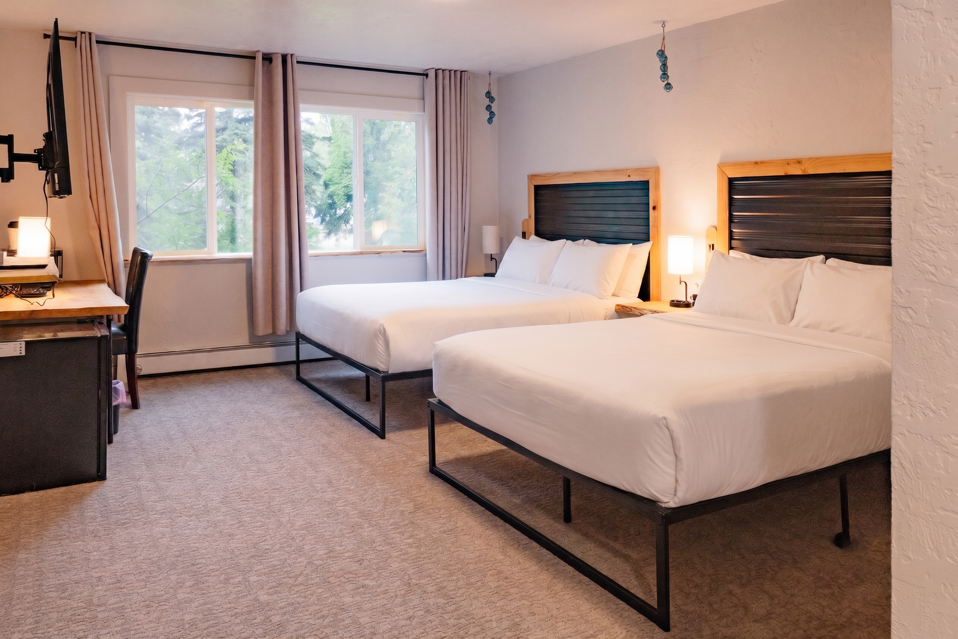 Hotel room with two twin beds, a desk, and a window with curtains