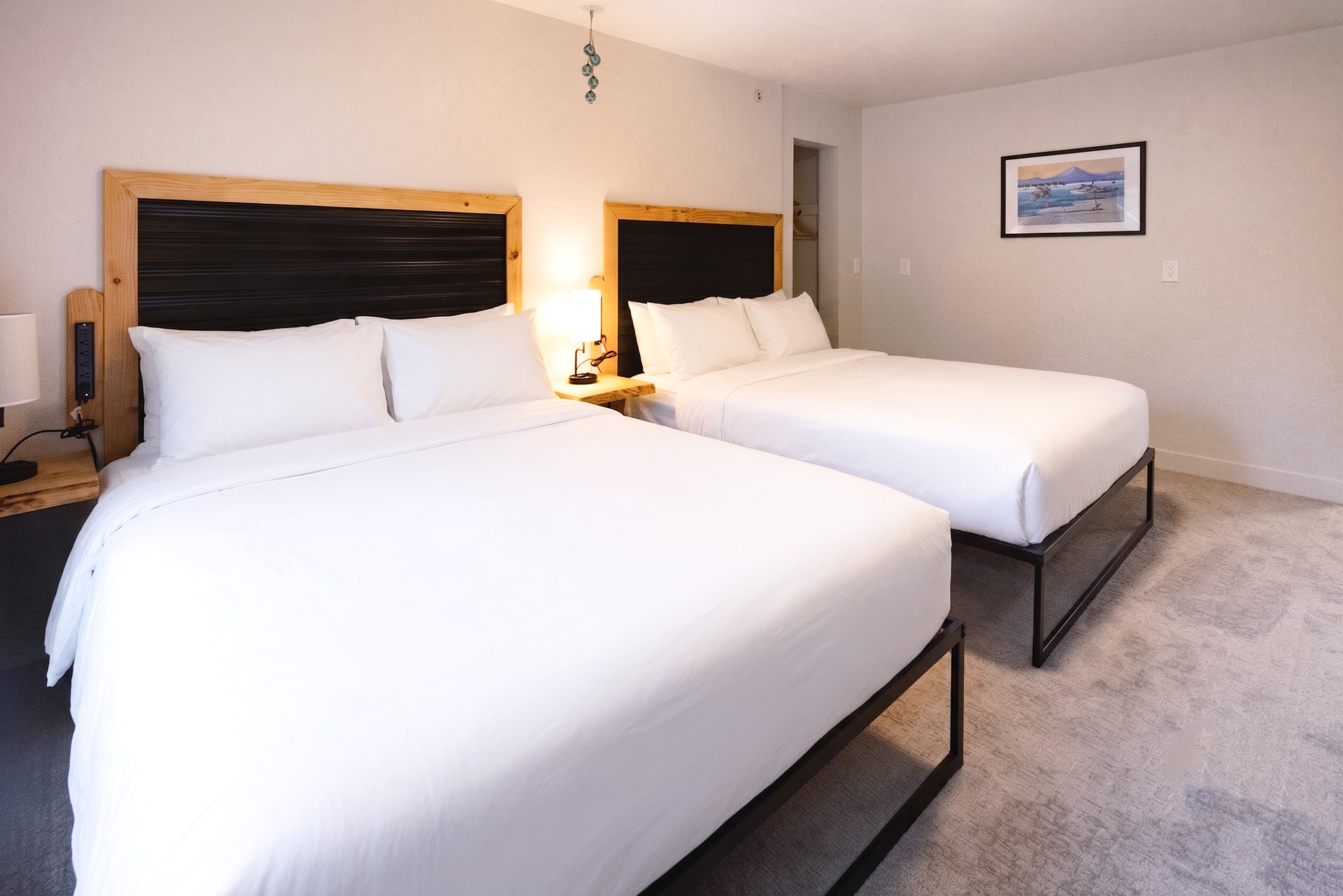 Hotel room with two neatly made white beds, dark wood headboards, and framed wall art