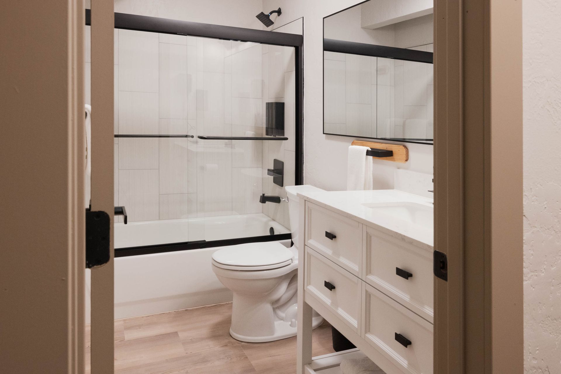 Modern bathroom with white vanity, toilet, and black-framed glass shower door