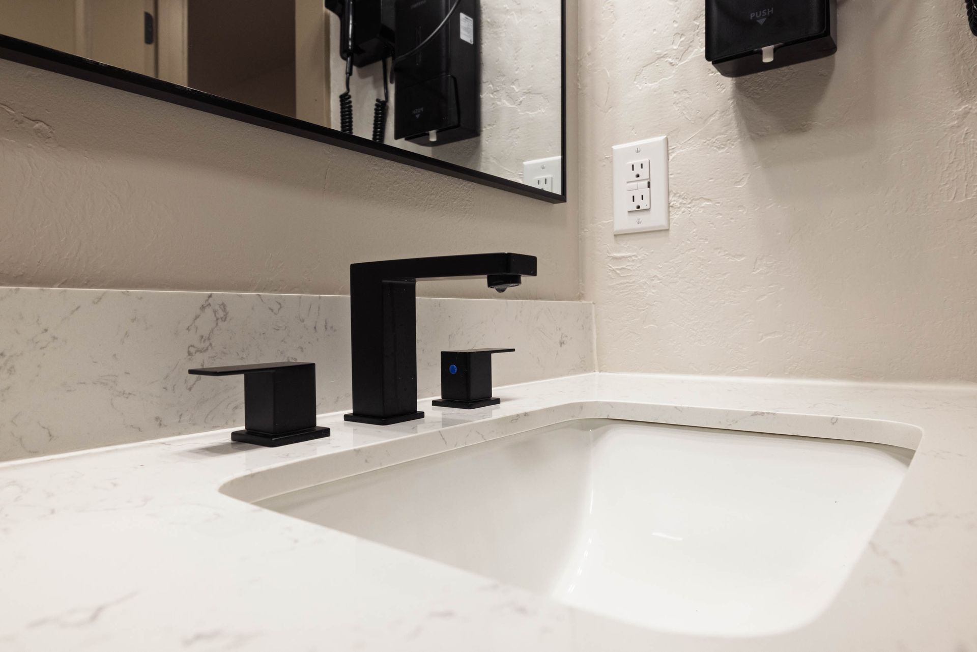 Modern bathroom sink with matte black faucet and fixtures on a white countertop