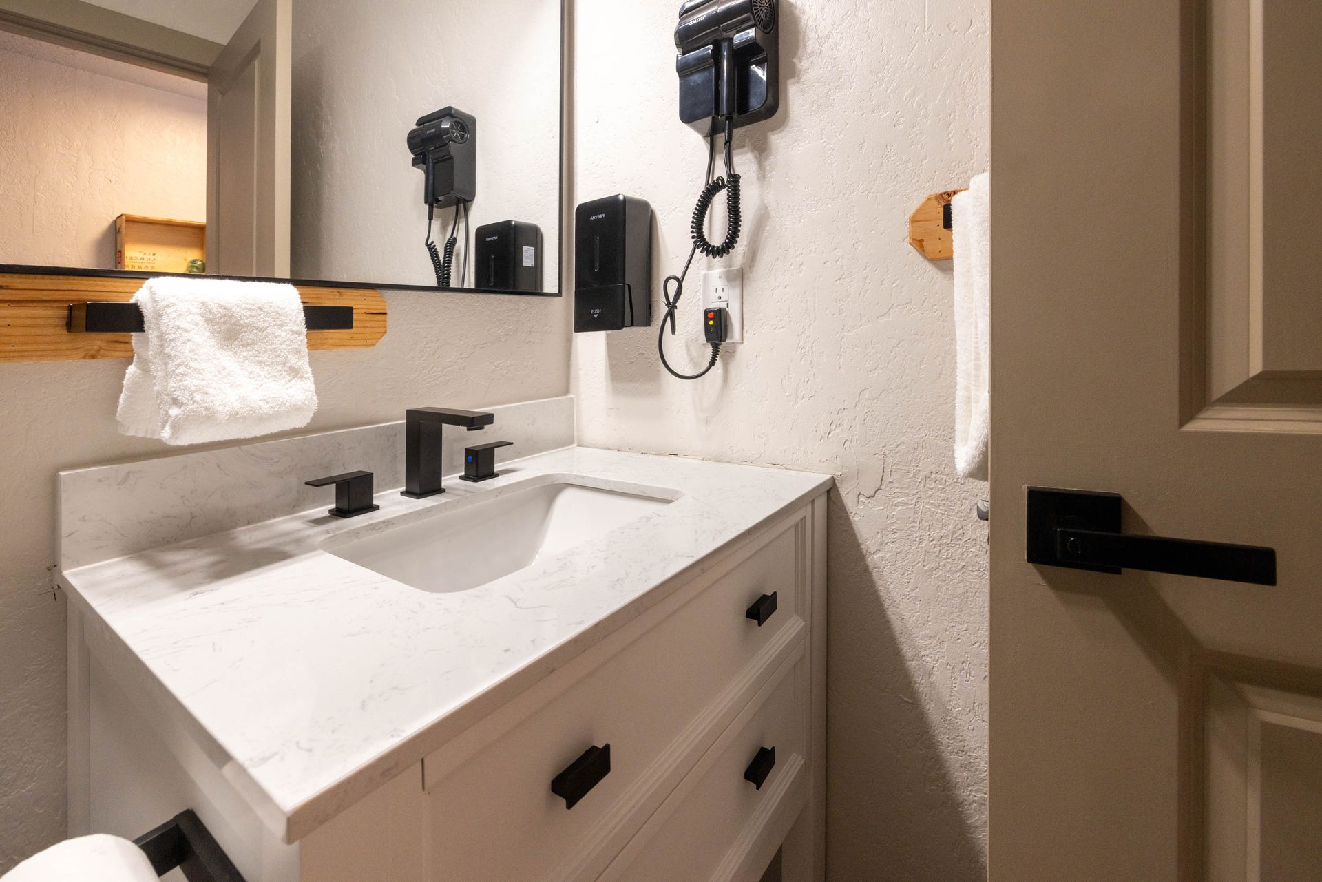 Modern bathroom vanity with sink, mirror, towel, and wall-mounted hair dryer