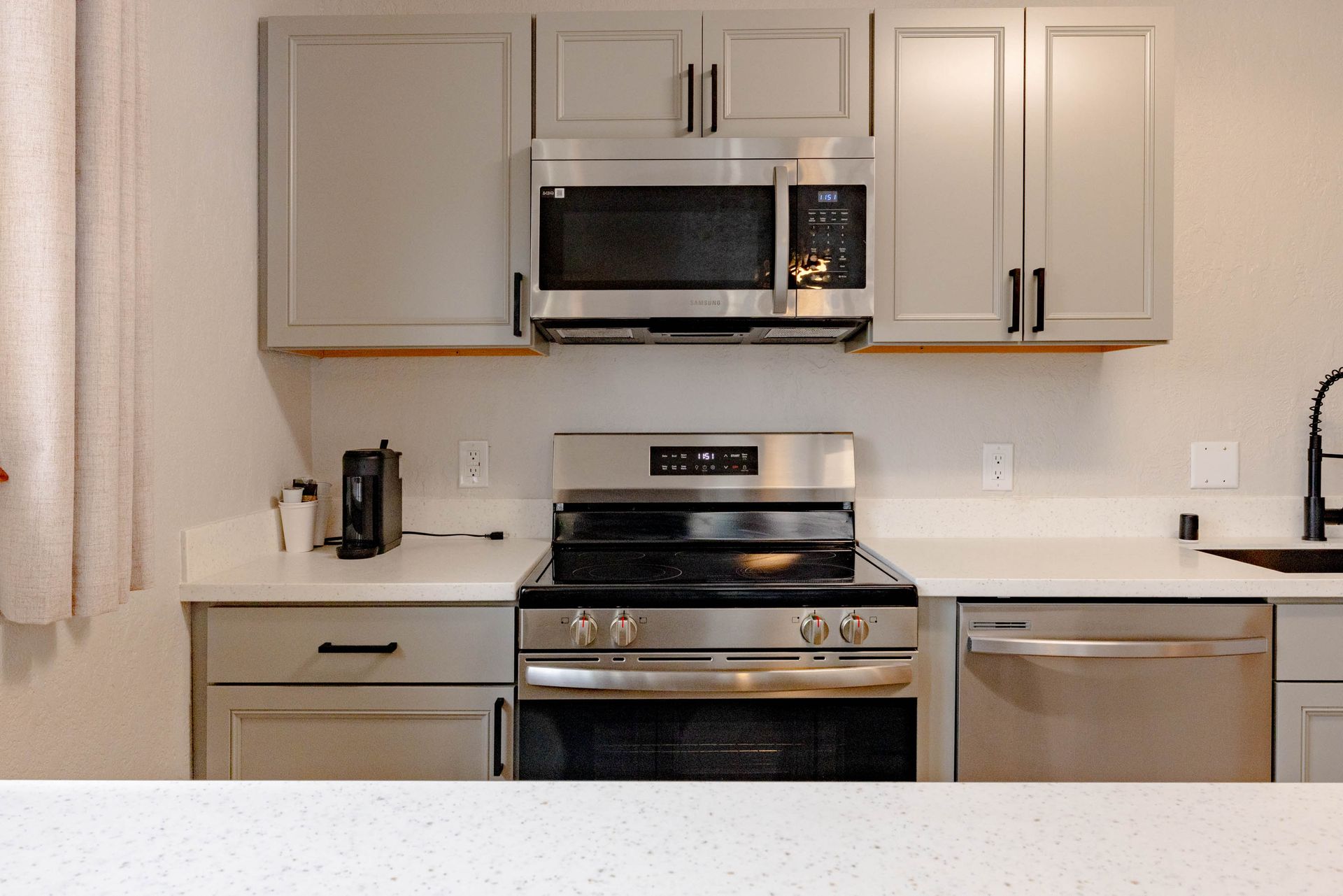 Modern kitchen with light cabinets, stainless steel appliances, and a white countertop