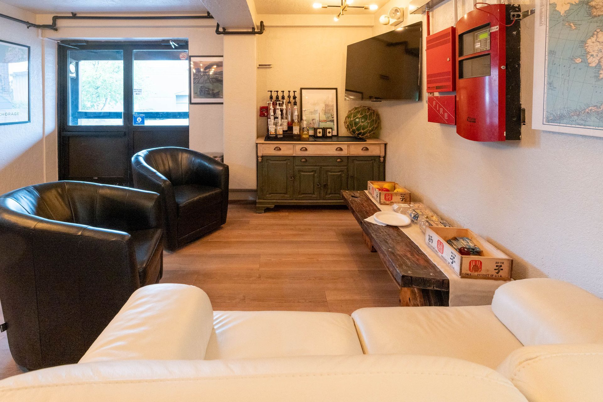 Modern living room with black chairs, white sofa, wooden floor, and red wall cabinets