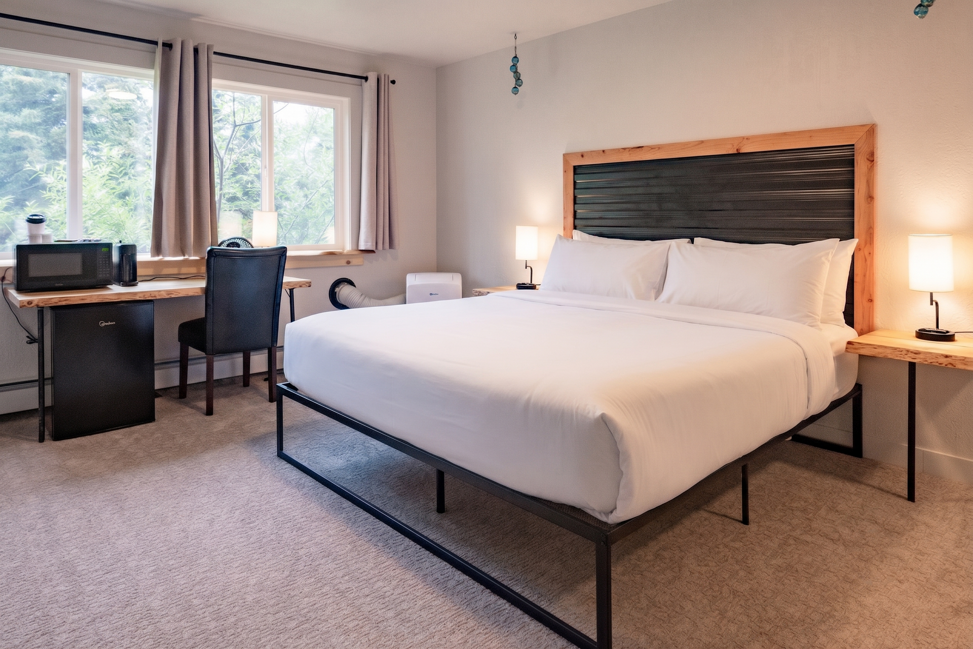Modern hotel room with a large bed, desk, chair, window, and bedside lamps