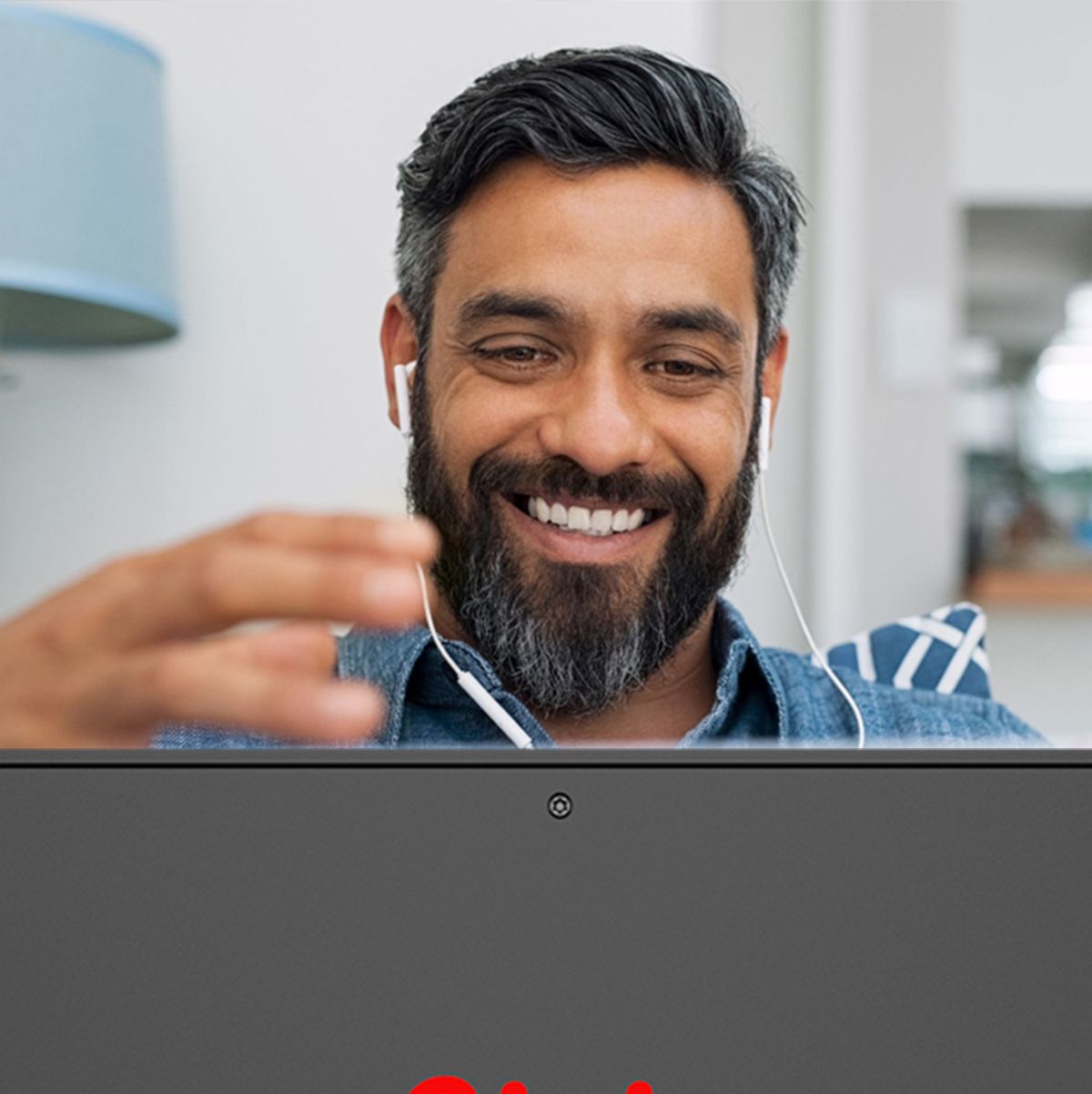 A man with a beard is smiling while using a laptop computer.