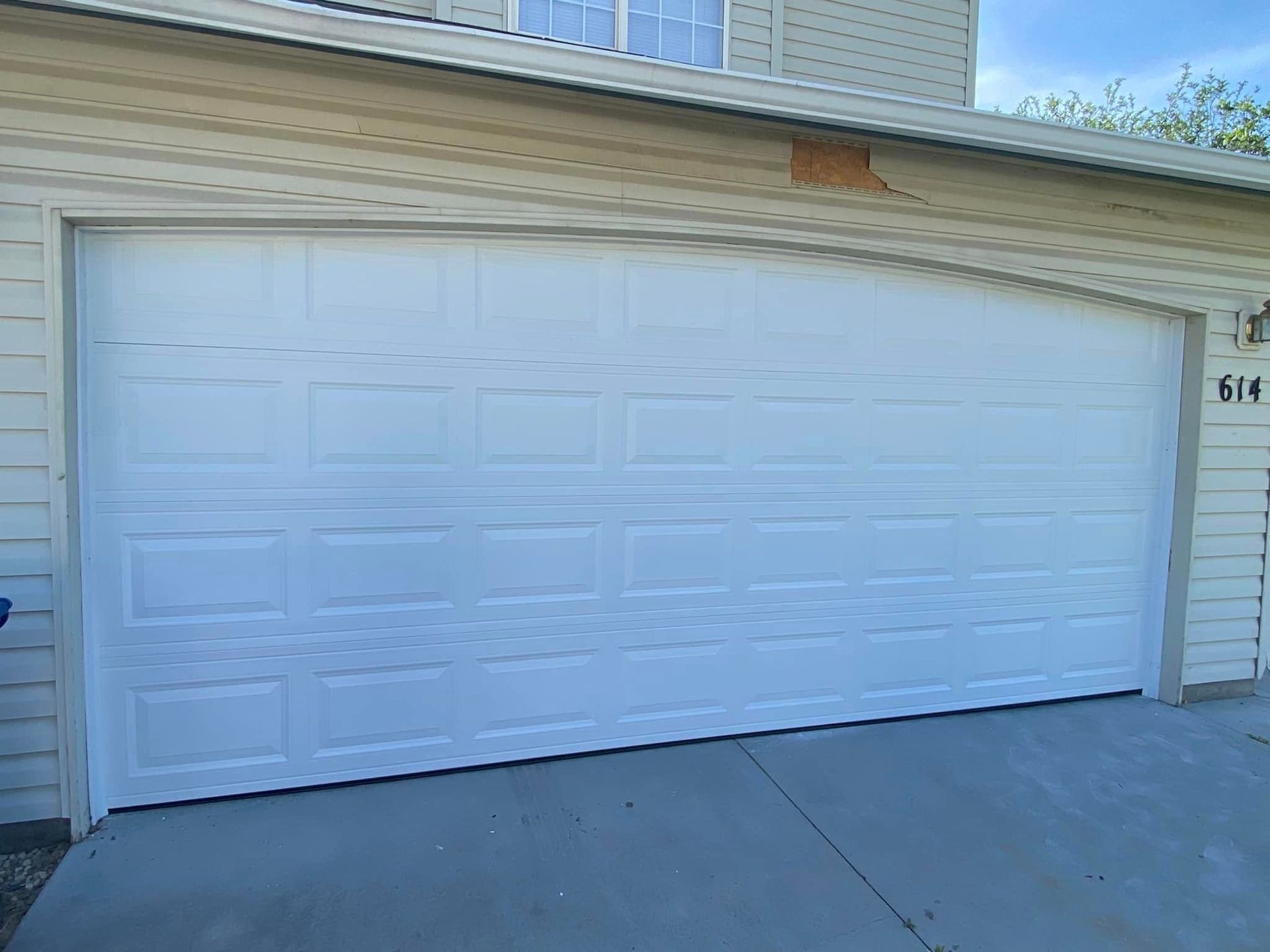 A white garage door is sitting in front of a house.