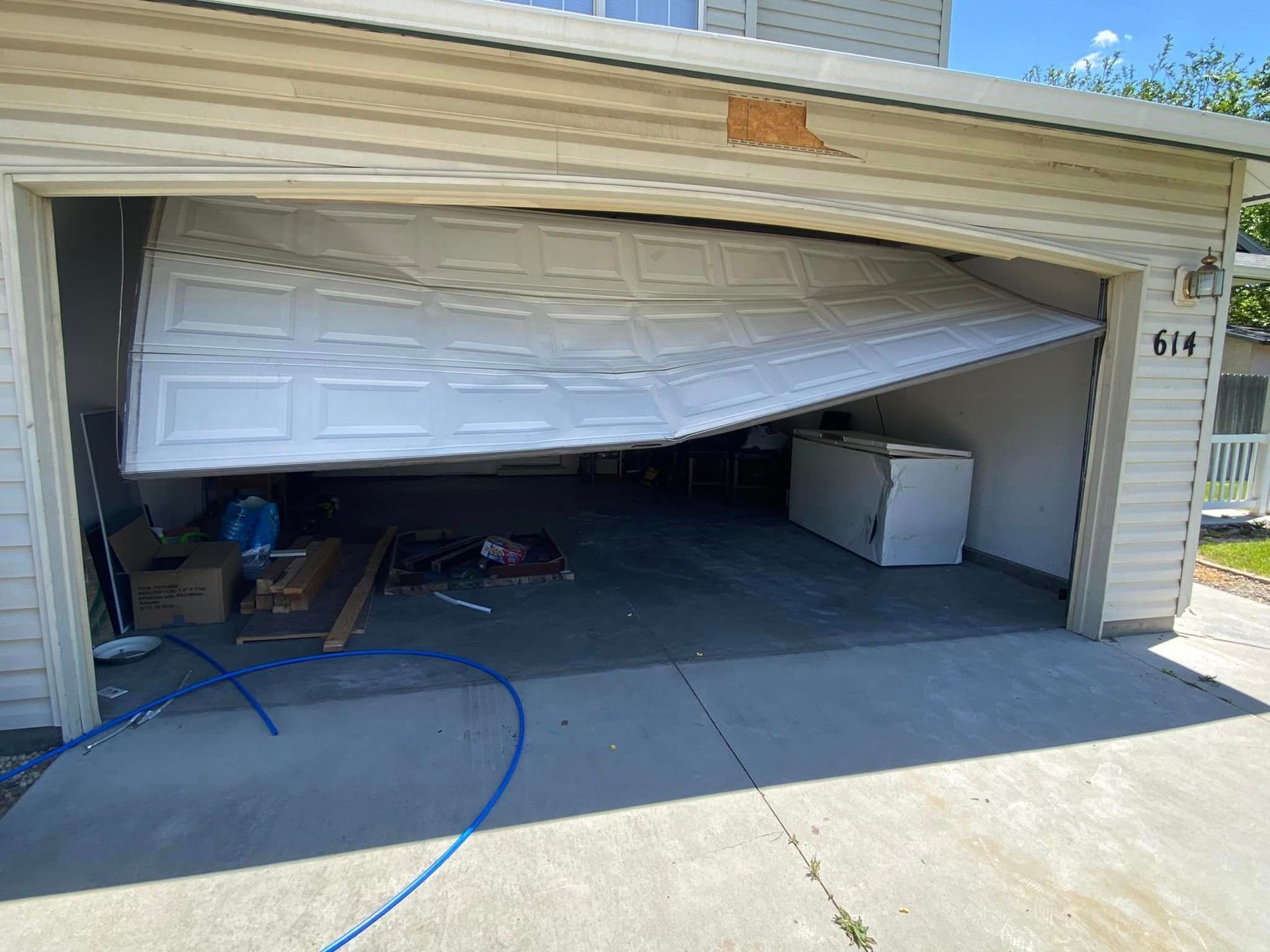A garage door is open and broken.