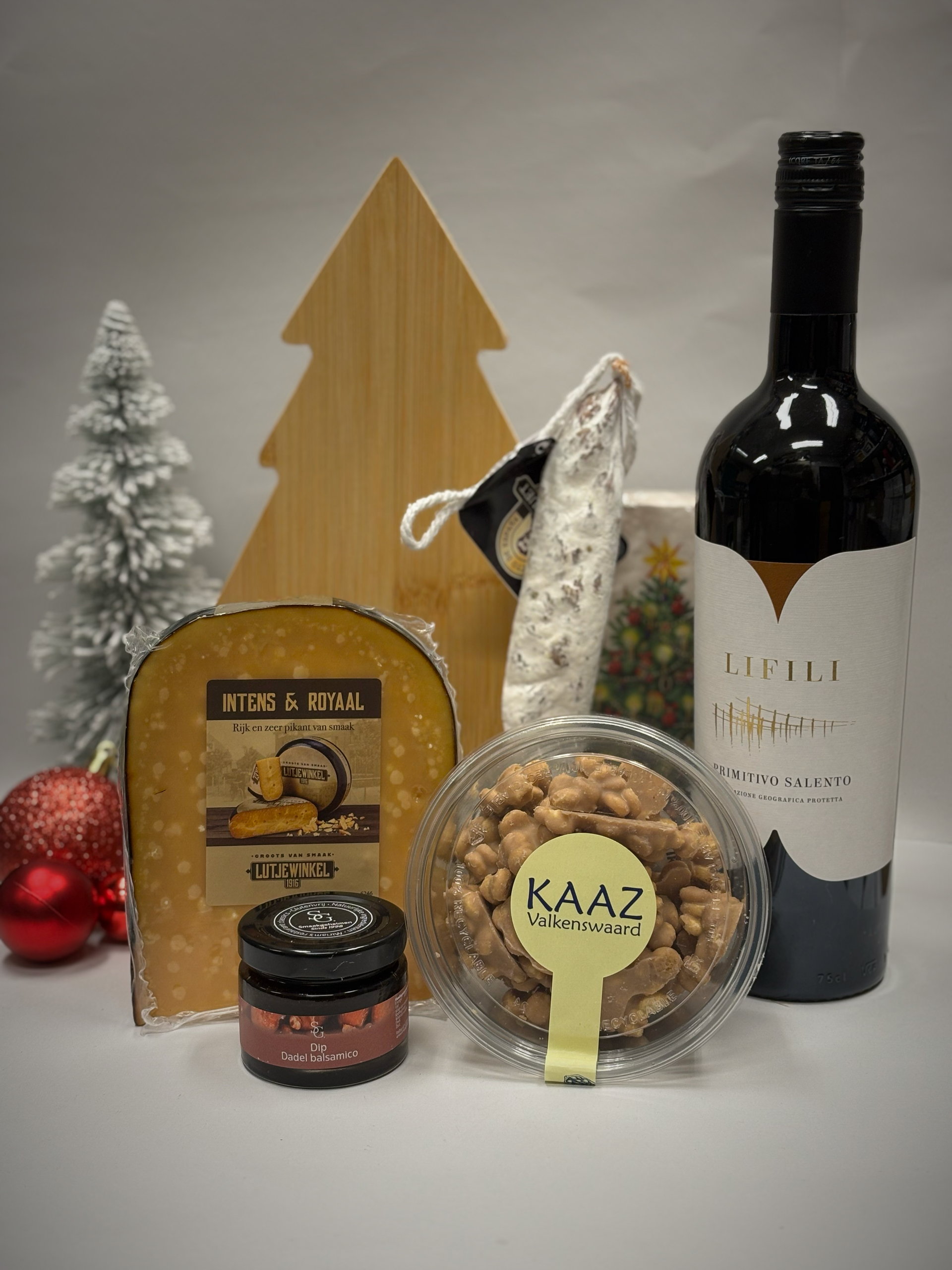 Kerstgeschenkmand met wijn, kaas, salami en zoetigheden; feestelijke setting.