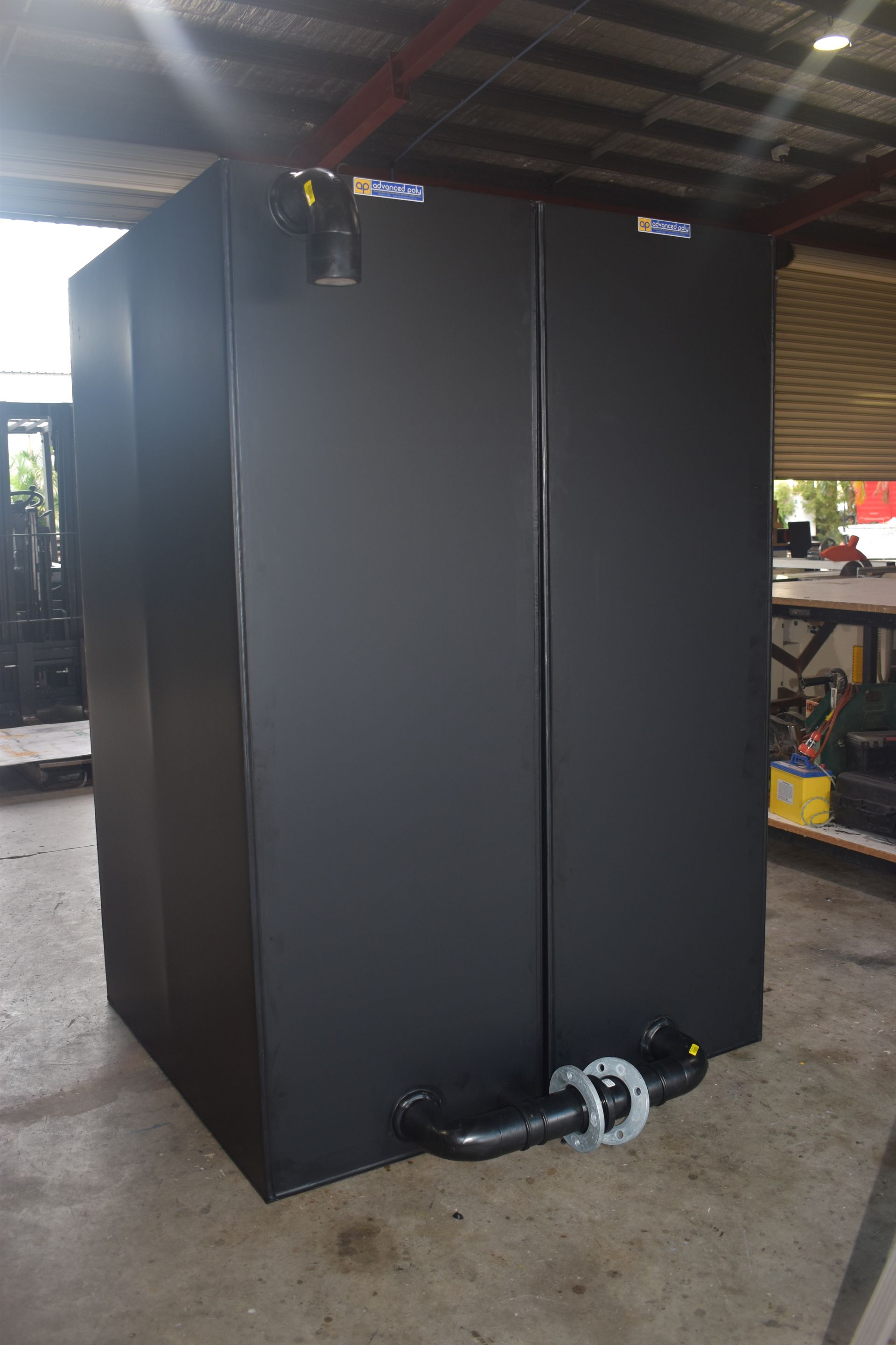 Large black industrial cabinet with a mounted pump at the base in a workshop setting — Advanced Poly in Darwin, NT