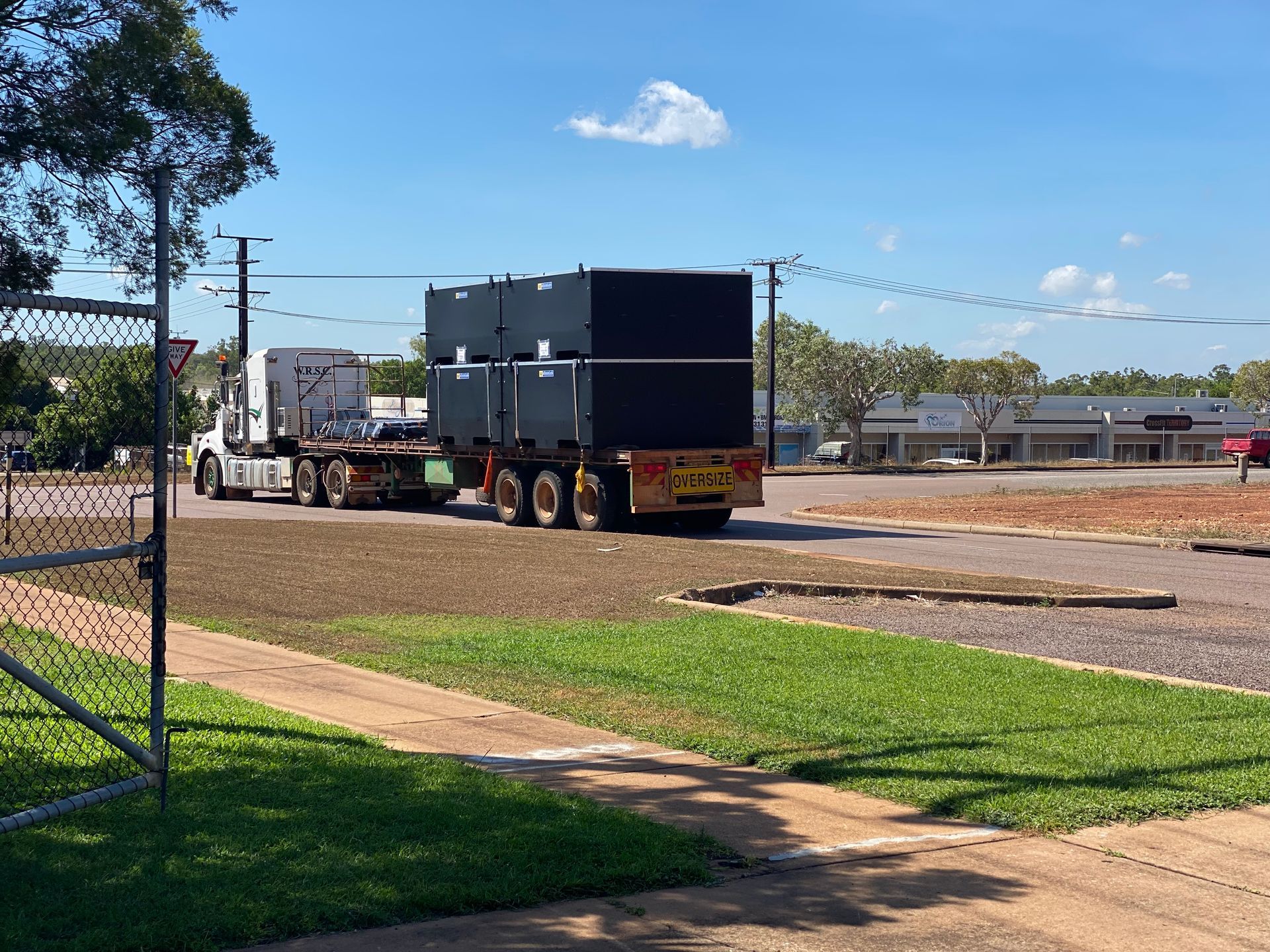 Truck towing a black trailer beside a fenced grassy area on a sunny day — Advanced Poly in Darwin, NT 