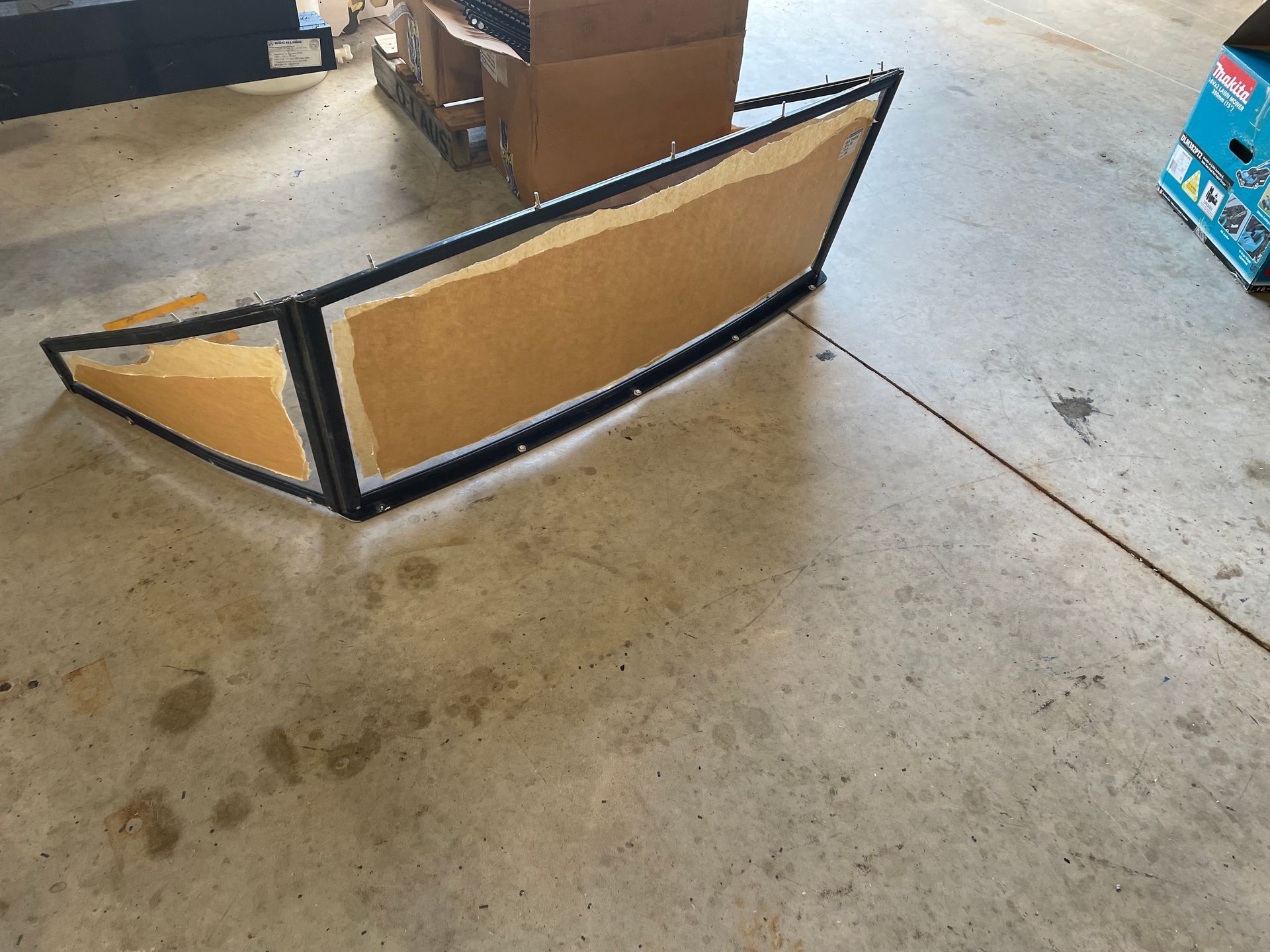 A long cardboard-and-black foam ramp or bumper lying on a concrete garage floor. — Advanced Poly in Darwin, NT