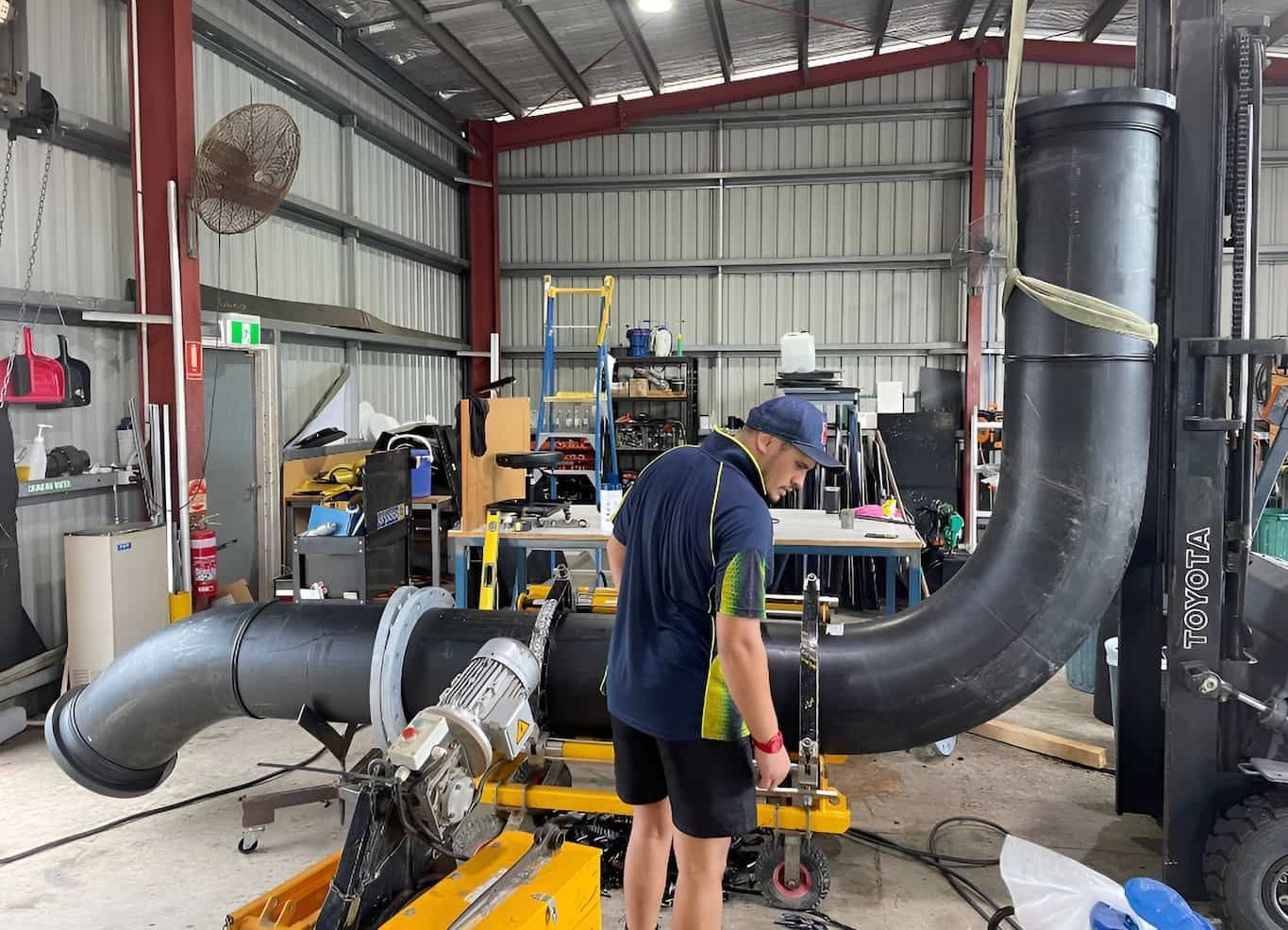 A Man Is Working on A Large Pipe in A Factory — Advanced Poly in Yarrawonga, NT