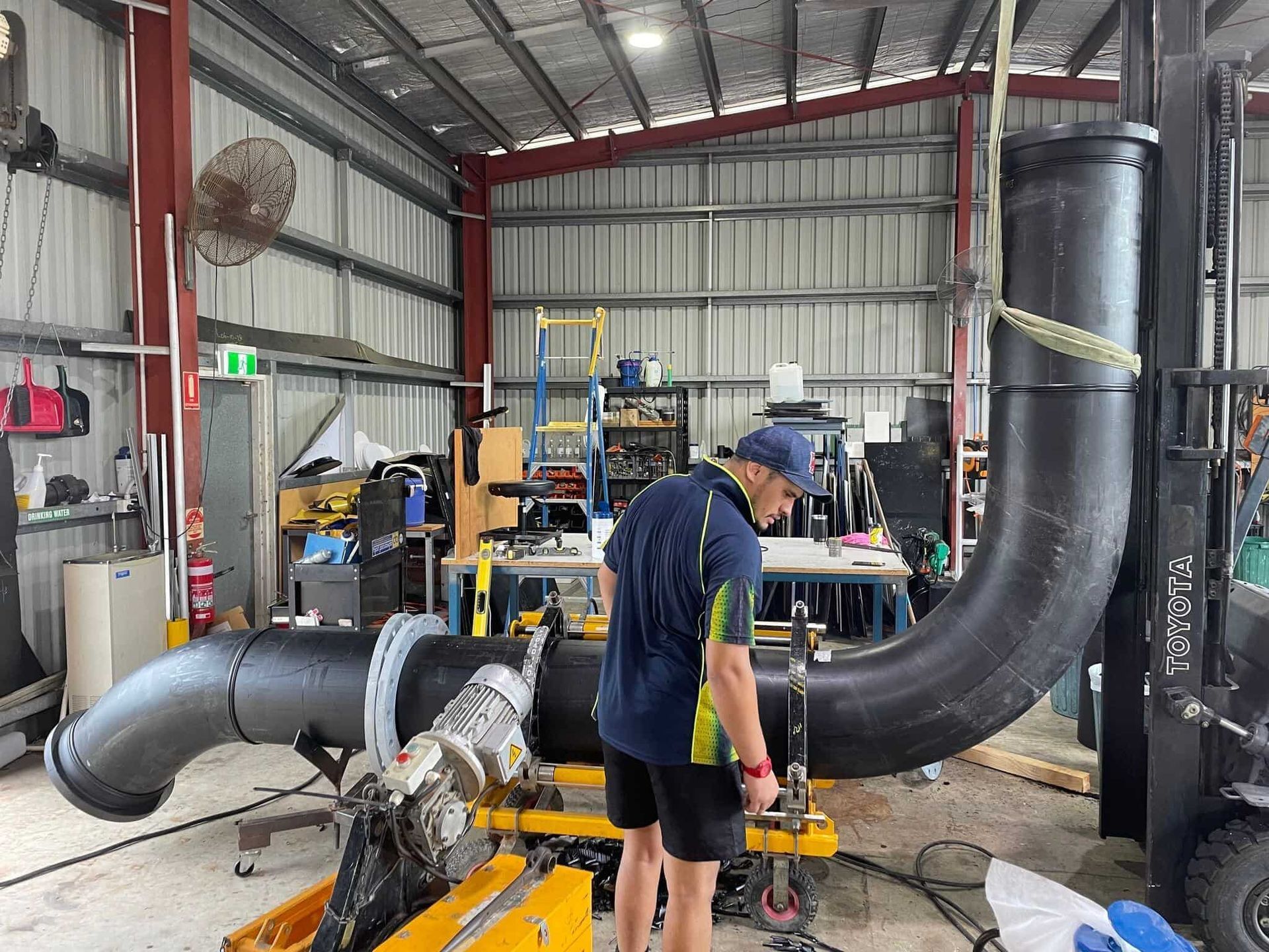 A man is working on a large pipe in a factory. — Advanced Poly in Yarrawonga, NT