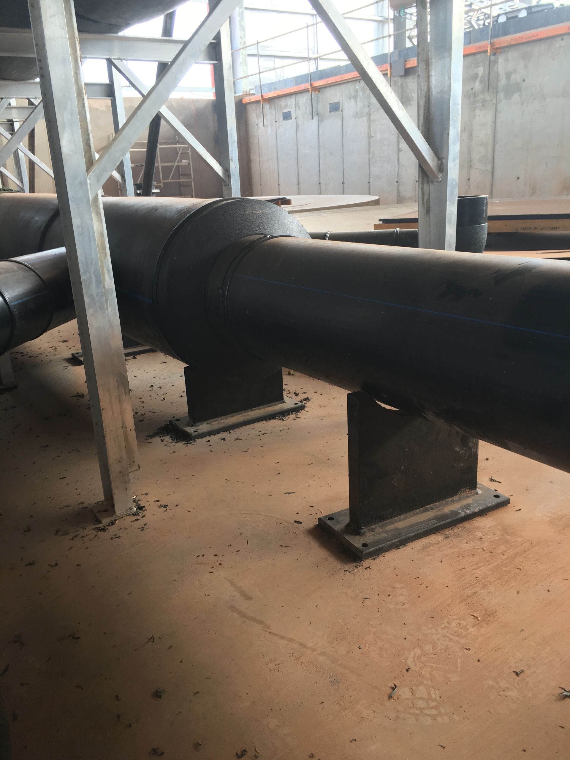 Large black industrial pipe on metal supports inside a warehouse-like facility — Advanced Poly in Darwin, NT