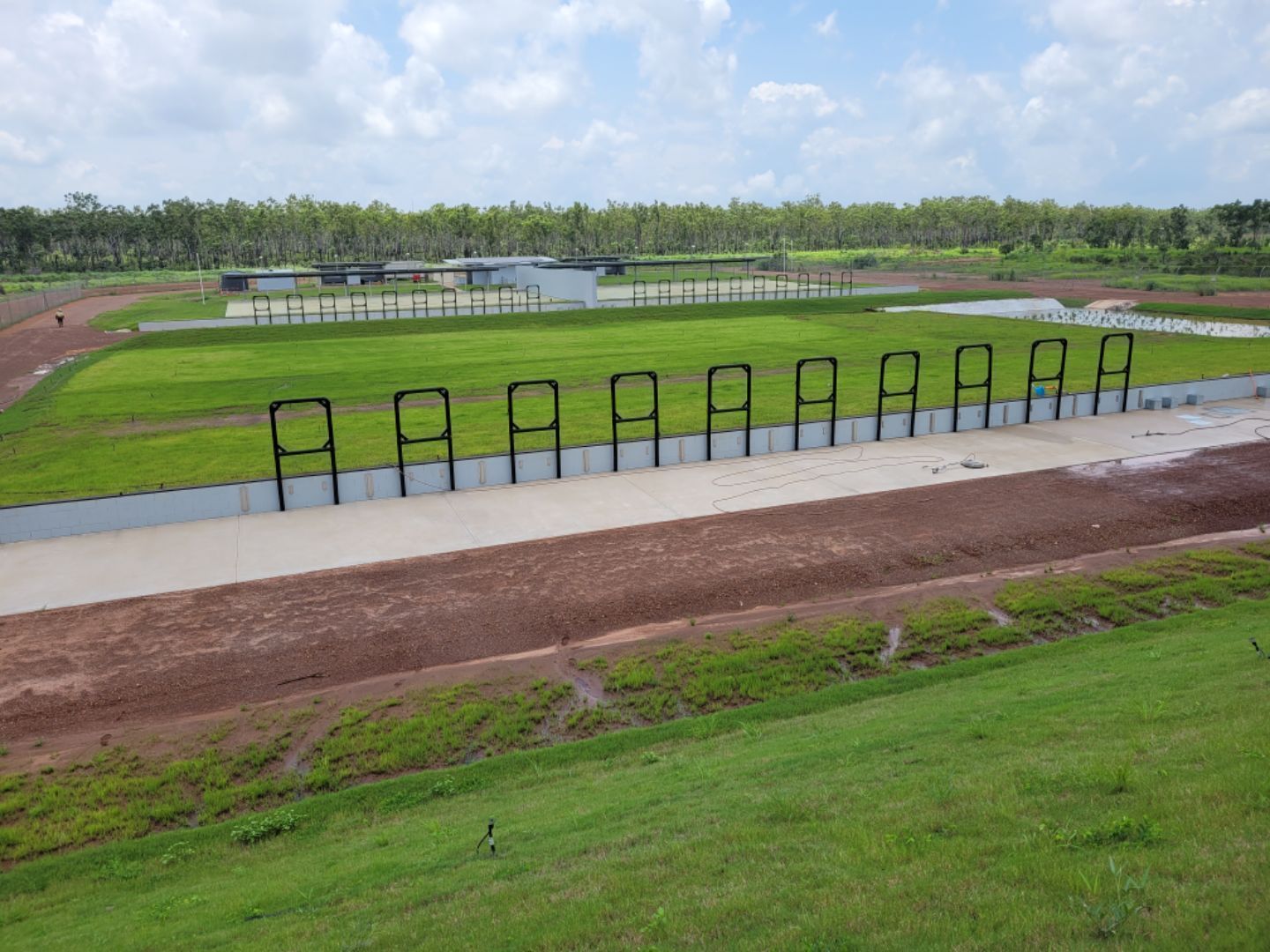 Row of black barriers beside a paved path overlooking a grassy field and distant trees — Advanced Poly in Darwin, NT