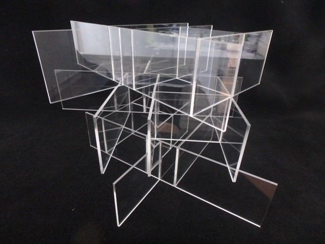 Transparent acrylic chairs stacked in an abstract arrangement against a black background — Advanced Poly in Darwin, NT