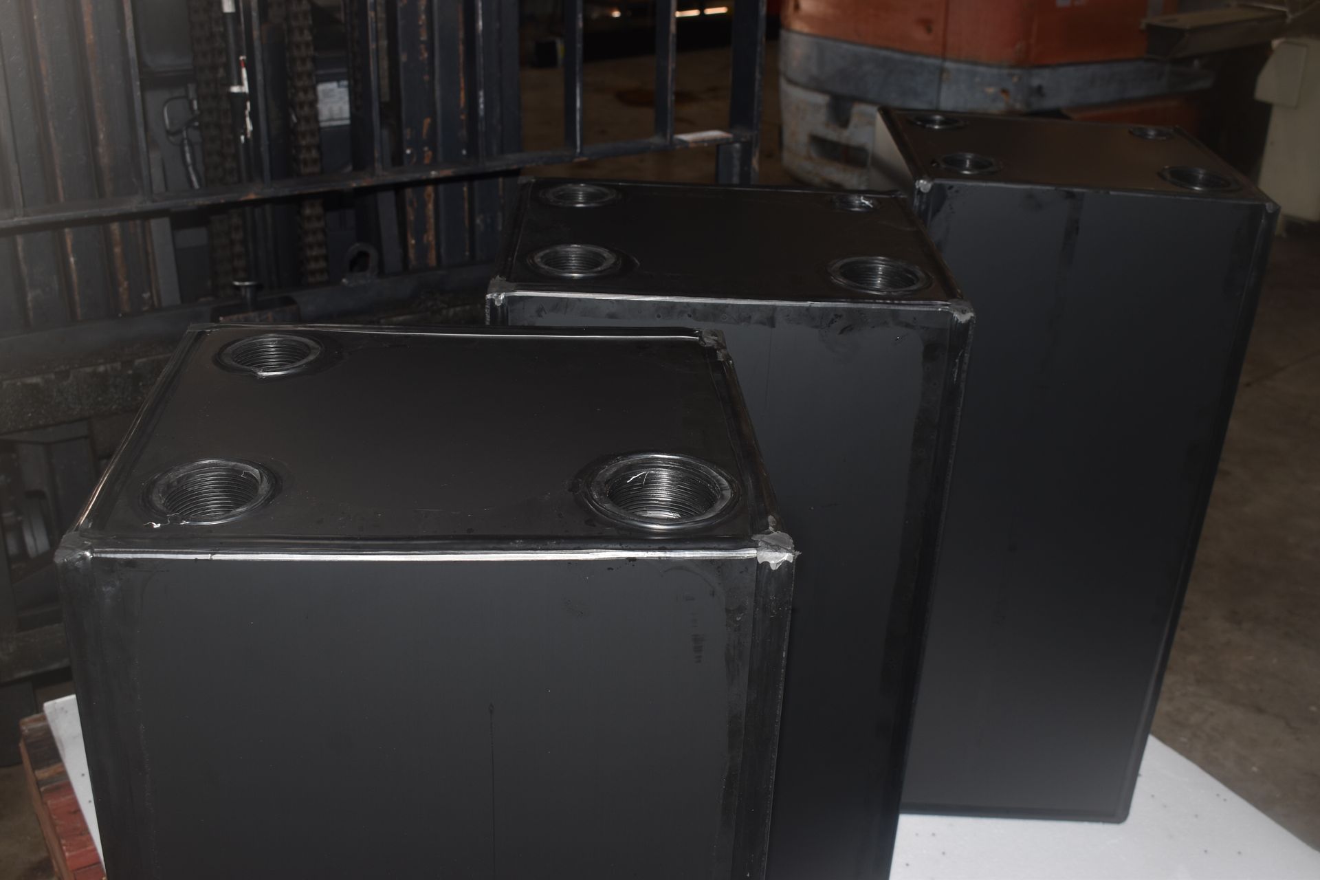 Three black metal cabinets or tanks with circular fittings on top in an industrial setting — Advanced Poly in Darwin, NT