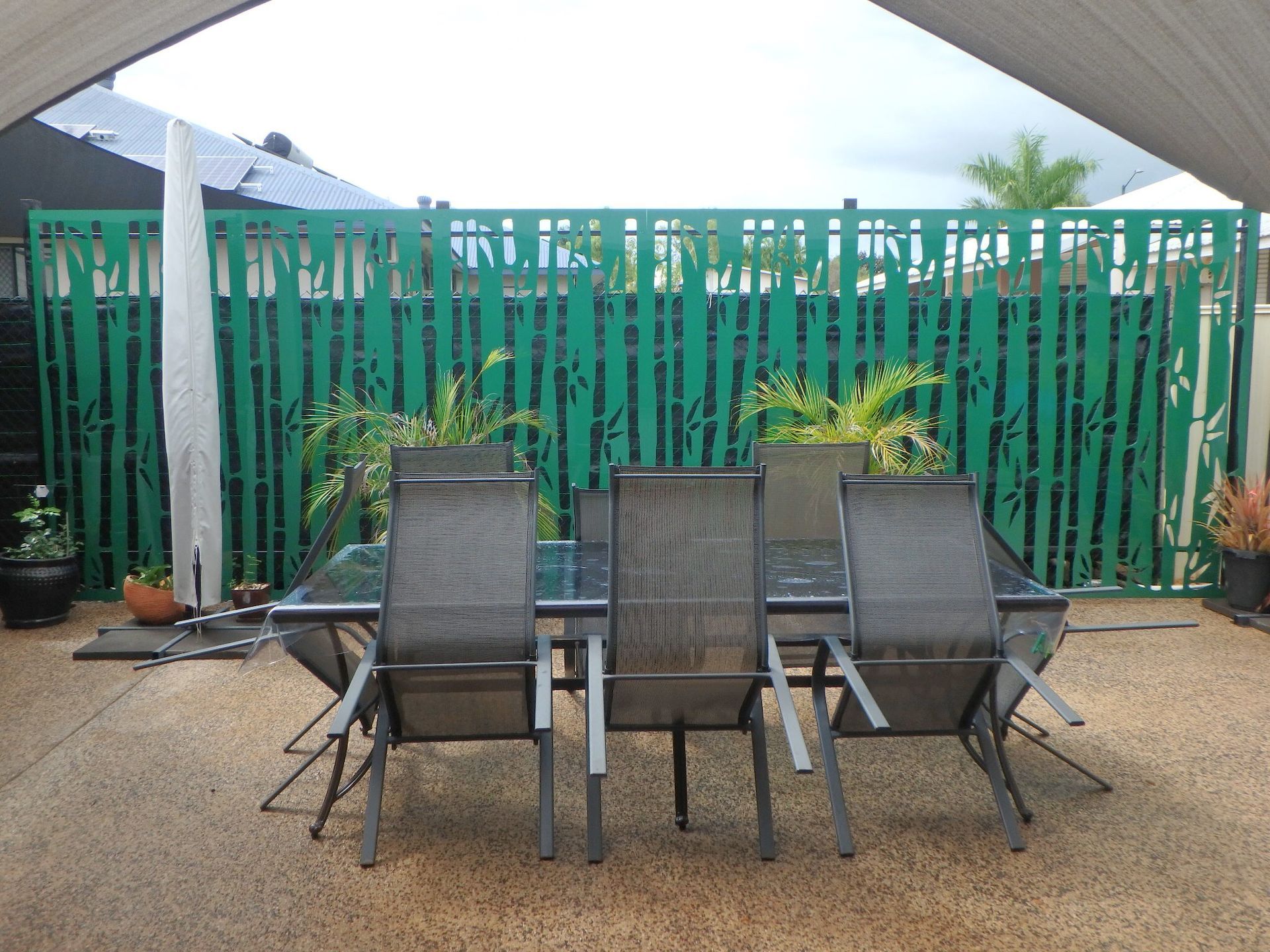 Patio with four gray chairs around a table, under a white canopy, in front of a green fence and potted plants — Advanced Poly in Darwin, NT — Advanced Poly in Darwin, NT 