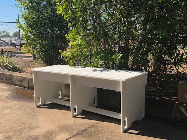 White outdoor bench-like storage cabinet on a paved area beside bushes and a road — Advanced Poly in Darwin, NT 