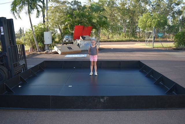 Child standing on a black outdoor stage in a park-like setting — Advanced Poly in Darwin, NT