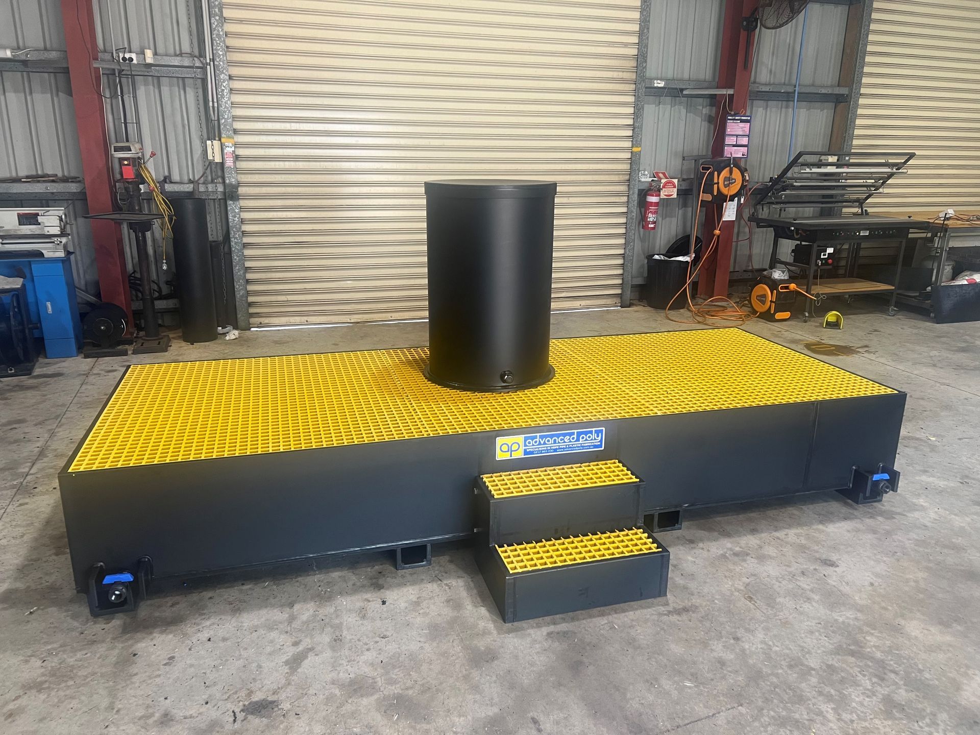 Industrial yellow-and-black platform with a central black cylinder in a warehouse, viewed from the front. — Advanced Poly in Darwin, NT