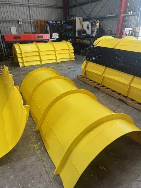 Yellow metal industrial machine parts stacked in a warehouse workshop. — Advanced Poly in Darwin, NT