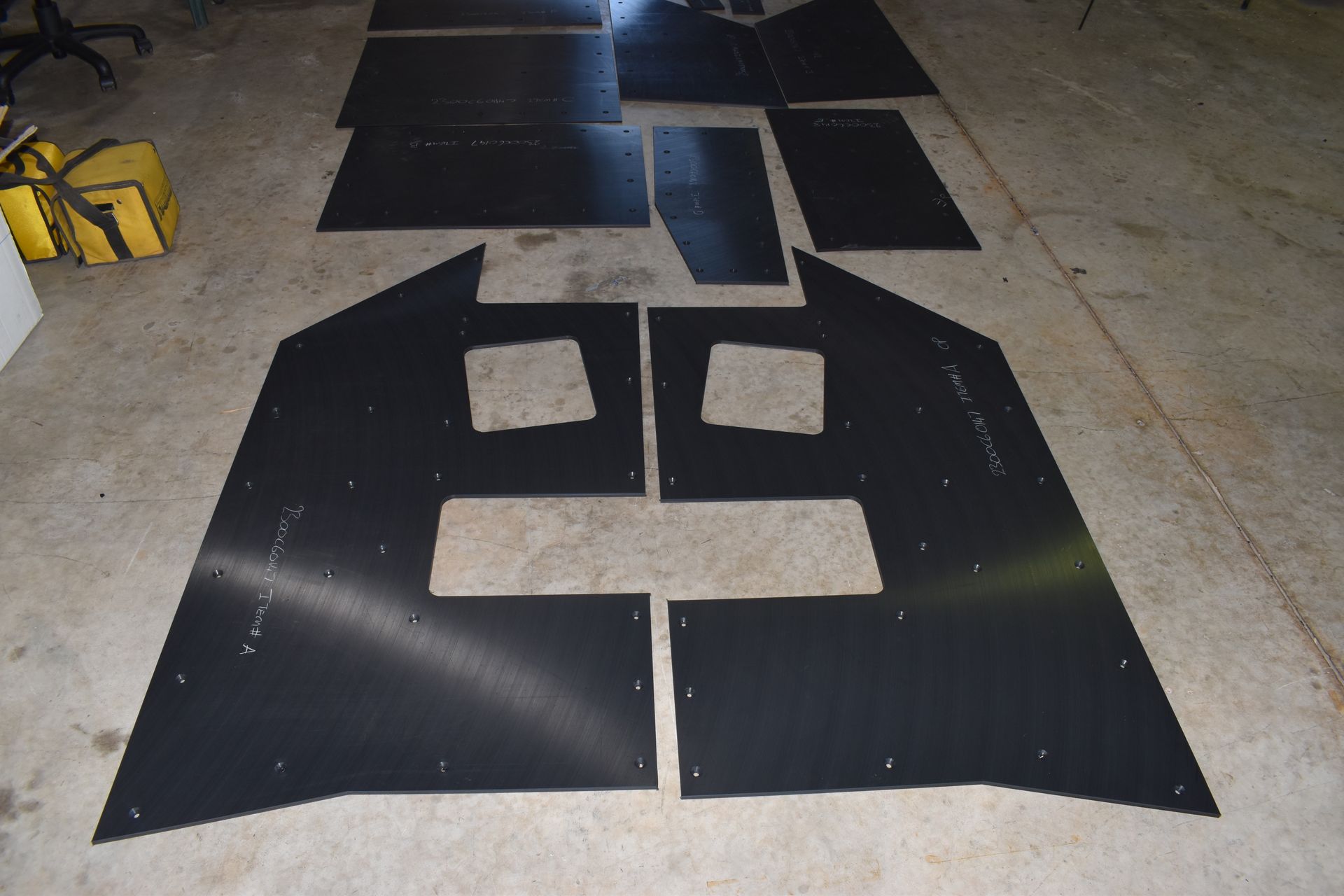 Black cutout pattern pieces arranged on a concrete floor, resembling a face with square eyes and mouth. — Advanced Poly in Darwin, NT — Advanced Poly in Darwin, NT 