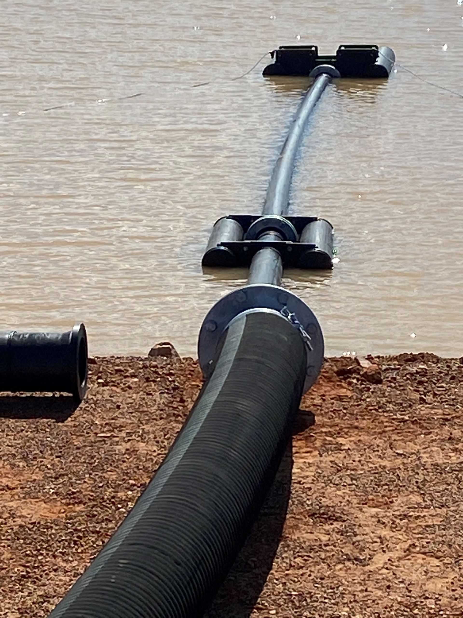 Black hose/cable runs across a floor, held by clips along a wall baseboard. — Advanced Poly in Darwin, NT