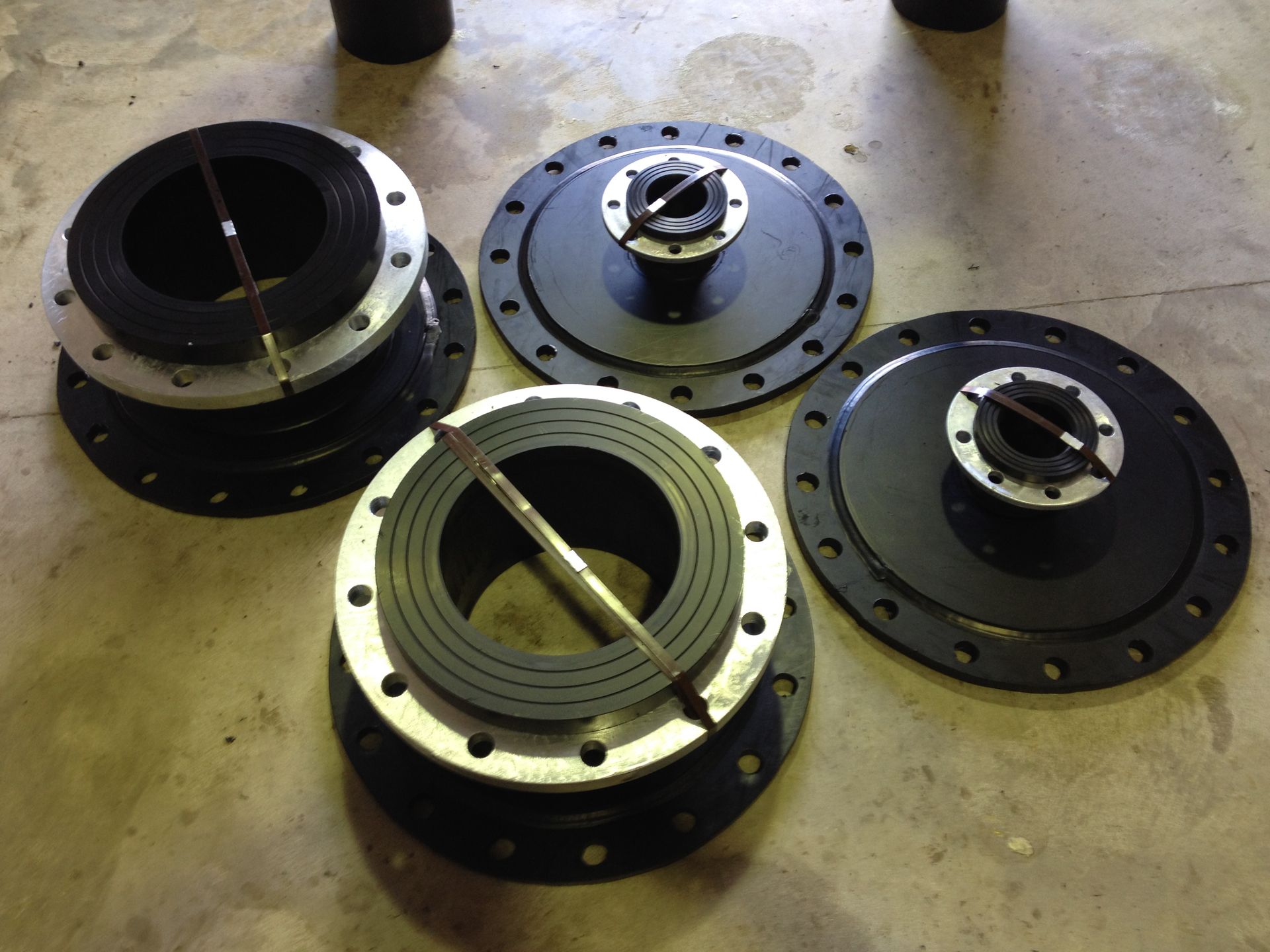 Three metal industrial flanges and couplings arranged on a concrete floor. — Advanced Poly in Darwin, NT