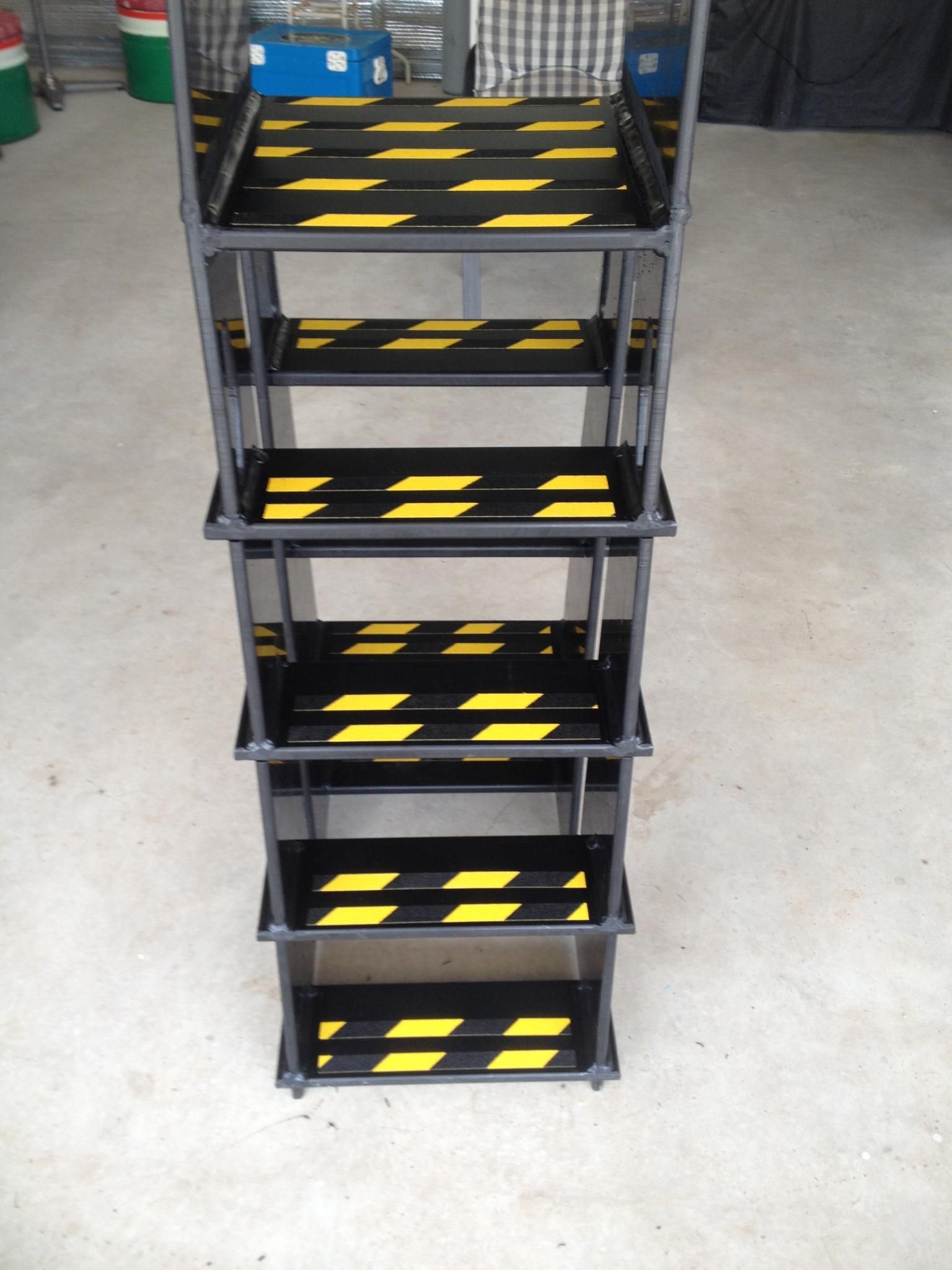 Stack of black plastic storage crates with yellow hazard stripes on a concrete floor. — Advanced Poly in Darwin, NT 