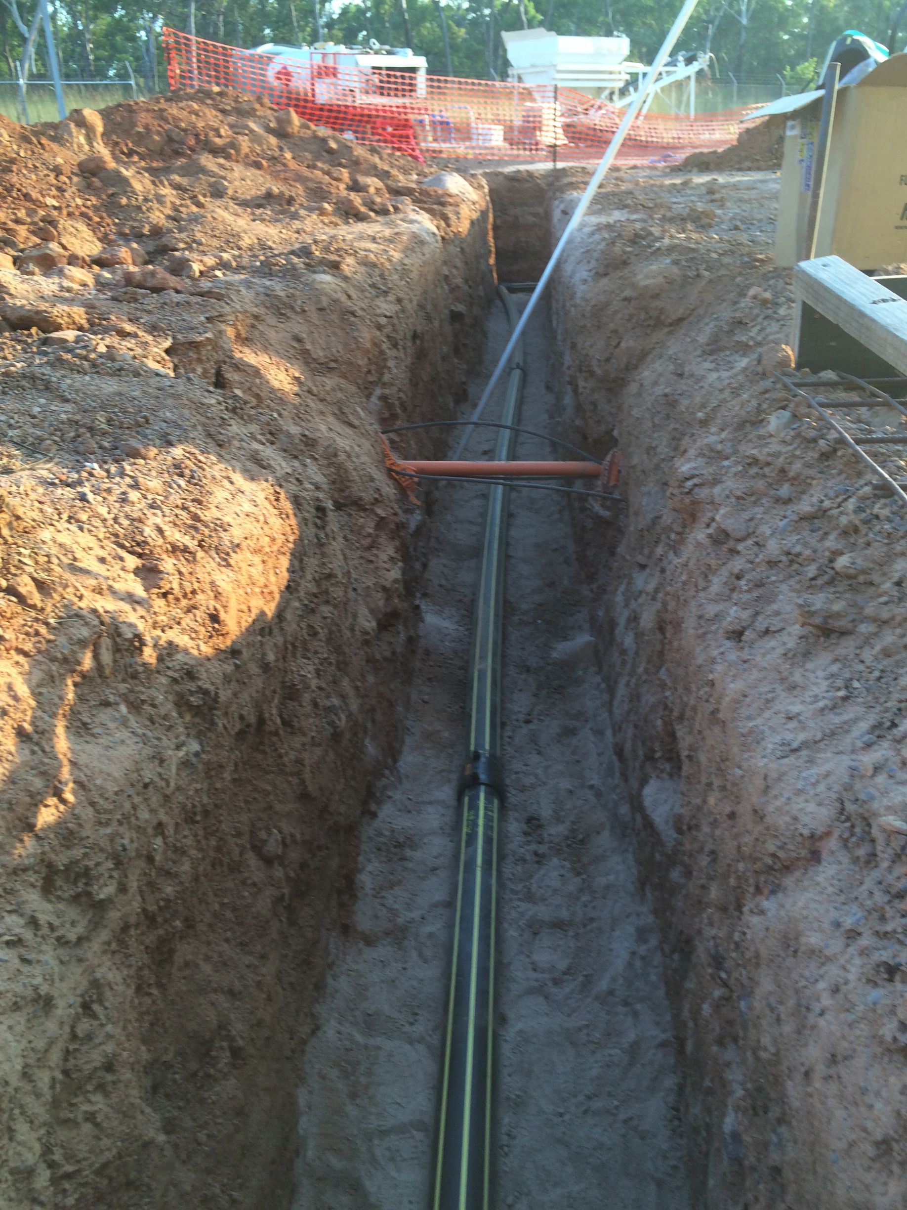 Utility trench with pipes laid in the ground between dirt walls at a construction site — Advanced Poly in Darwin, NT