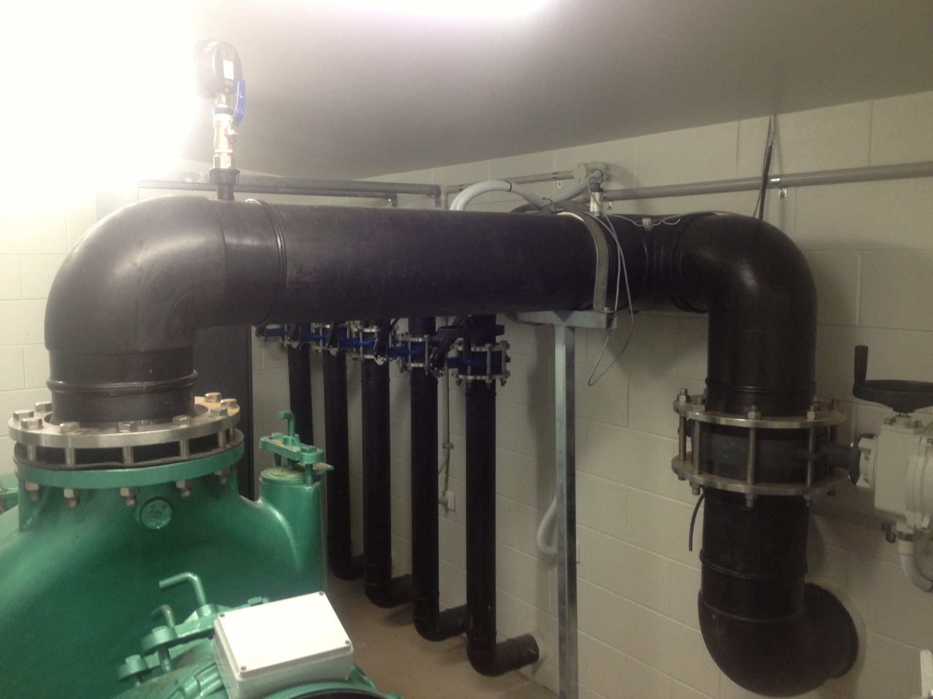 Industrial pipes and valves connected to green machinery in a utility room — Advanced Poly in Darwin, NT
