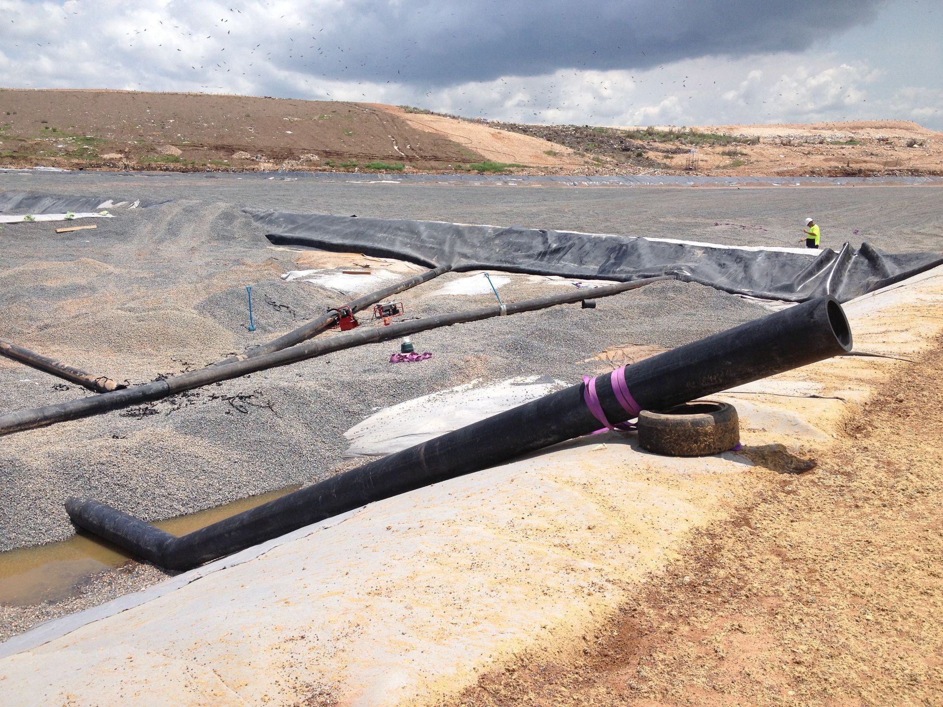 Black broken wind turbine blade lying on a rocky shoreline under cloudy skies — Advanced Poly in Darwin, NT — Advanced Poly in Darwin, NT 