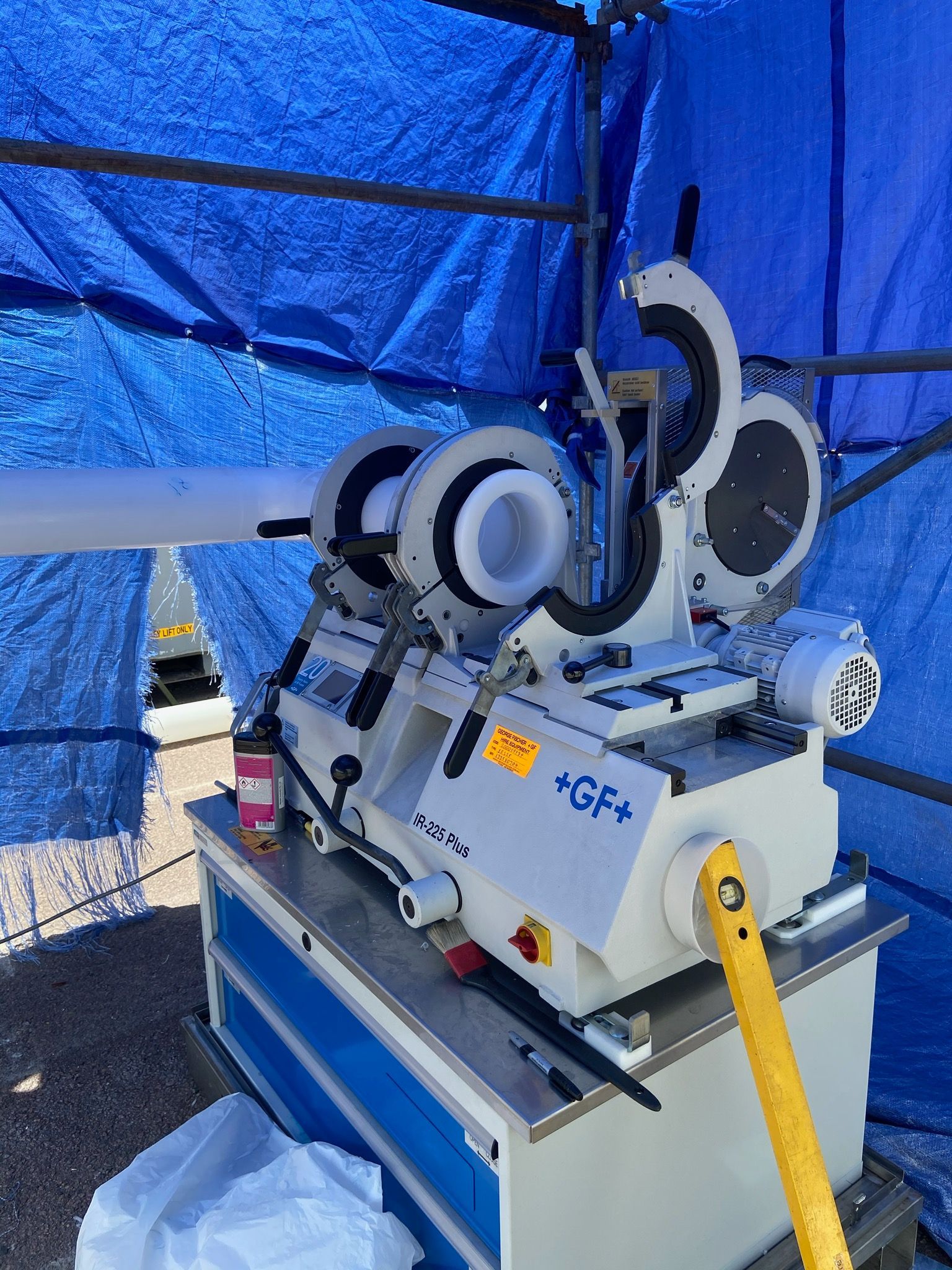 Industrial machine under blue tent with yellow hose and multiple wheels on a worktable — Advanced Poly in Darwin, NT