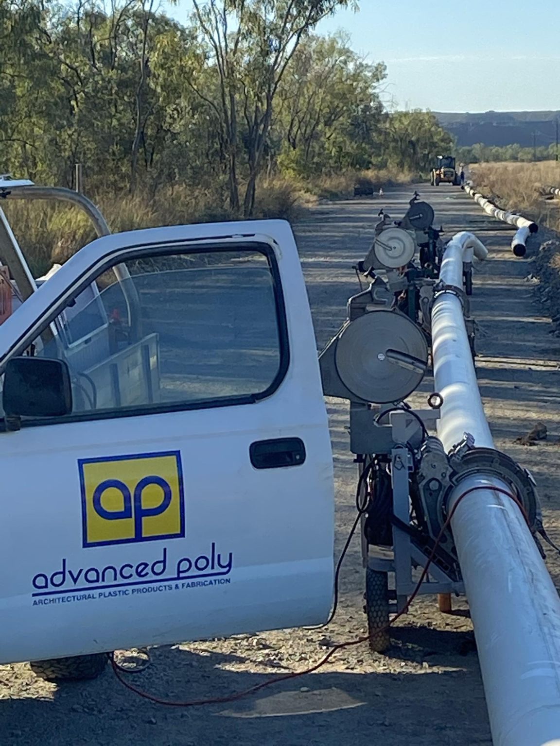 White utility truck with “advanced poly” logo beside a large pipeline in a rural outdoor setting — Advanced Poly in Darwin, NT