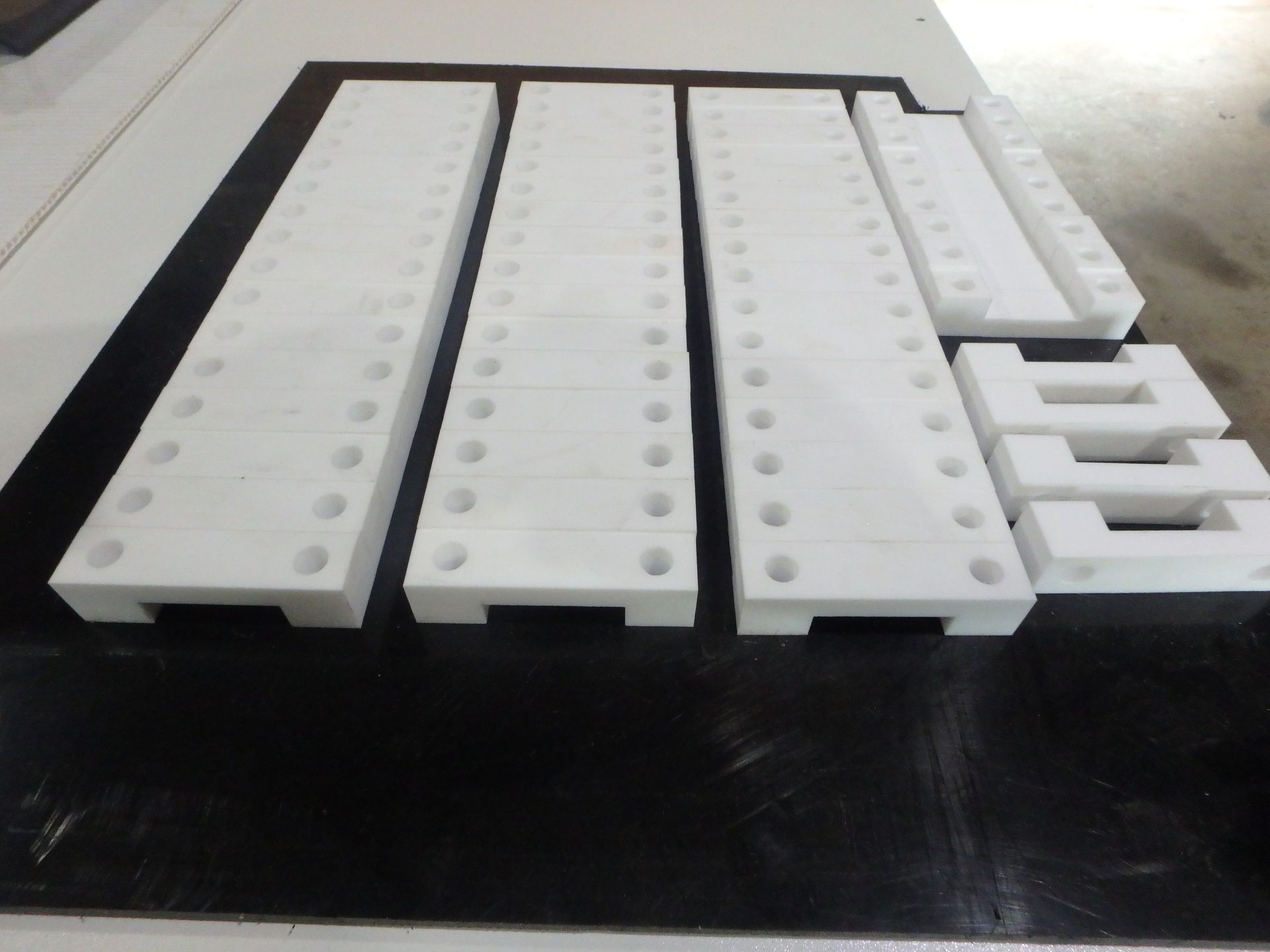 White plastic organizer trays with holes, arranged in rows on a black surface. — Advanced Poly in Darwin, NT — Advanced Poly in Darwin, NT 