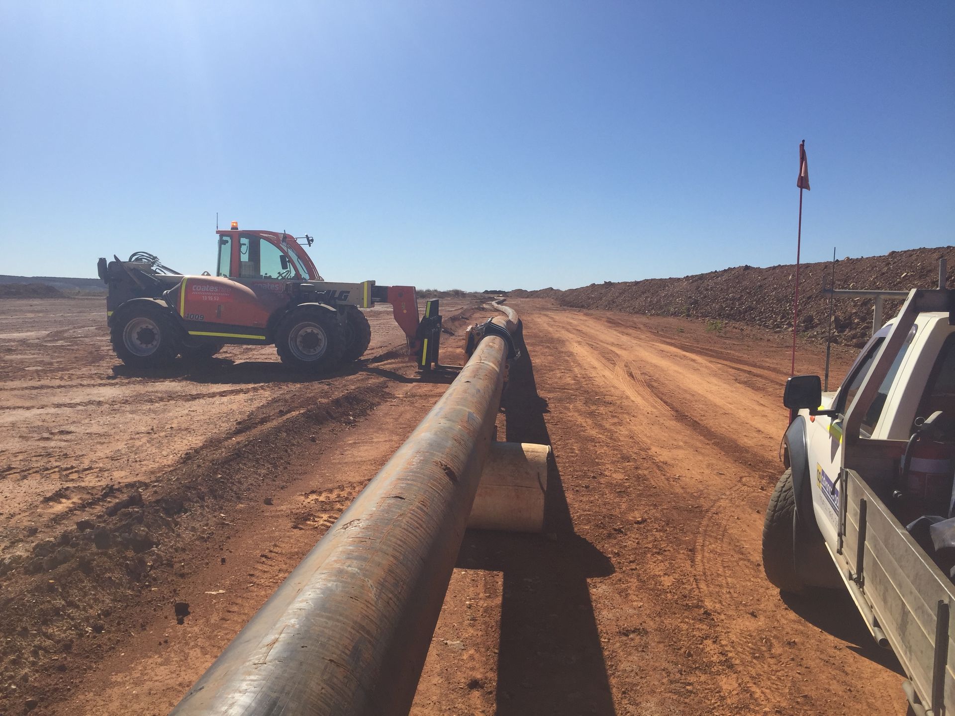 Workers and a tractor align a long pipeline in a dusty construction site under a clear sky — Advanced Poly in Darwin, NT