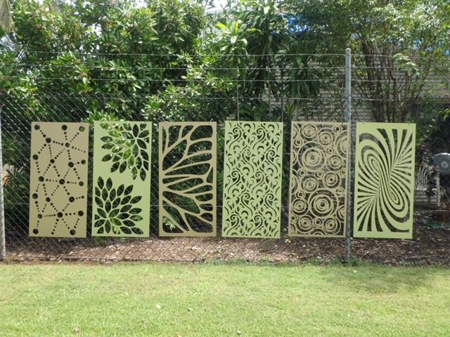 Decorative metal garden panels with leaf and spiral cutouts along a wire fence in a grassy yard — Advanced Poly in Darwin, NT — Advanced Poly in Darwin, NT 