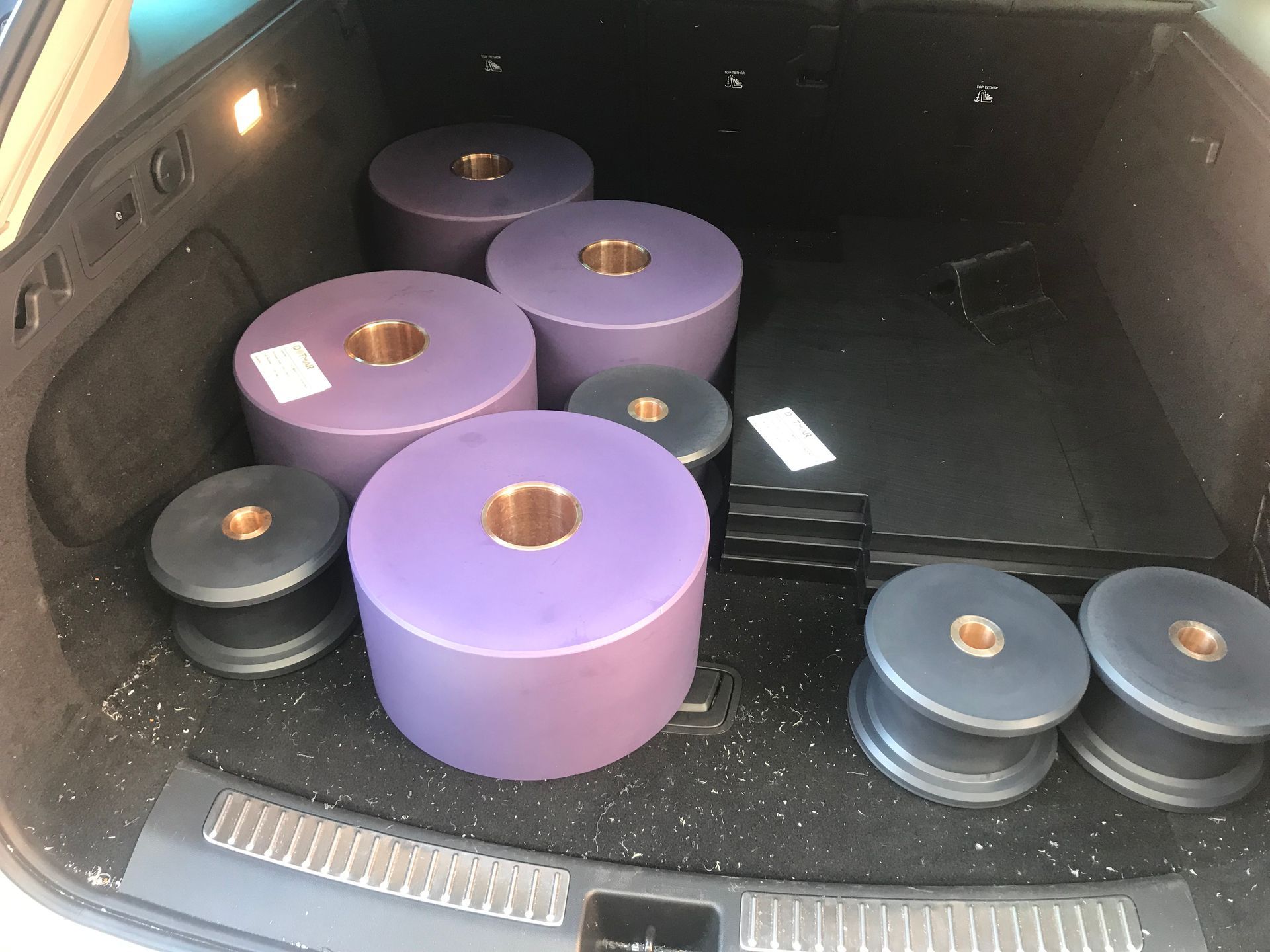Trunk of a car filled with large purple and black cylindrical weights arranged in rows — Advanced Poly in Darwin, NT — Advanced Poly in Darwin, NT 
