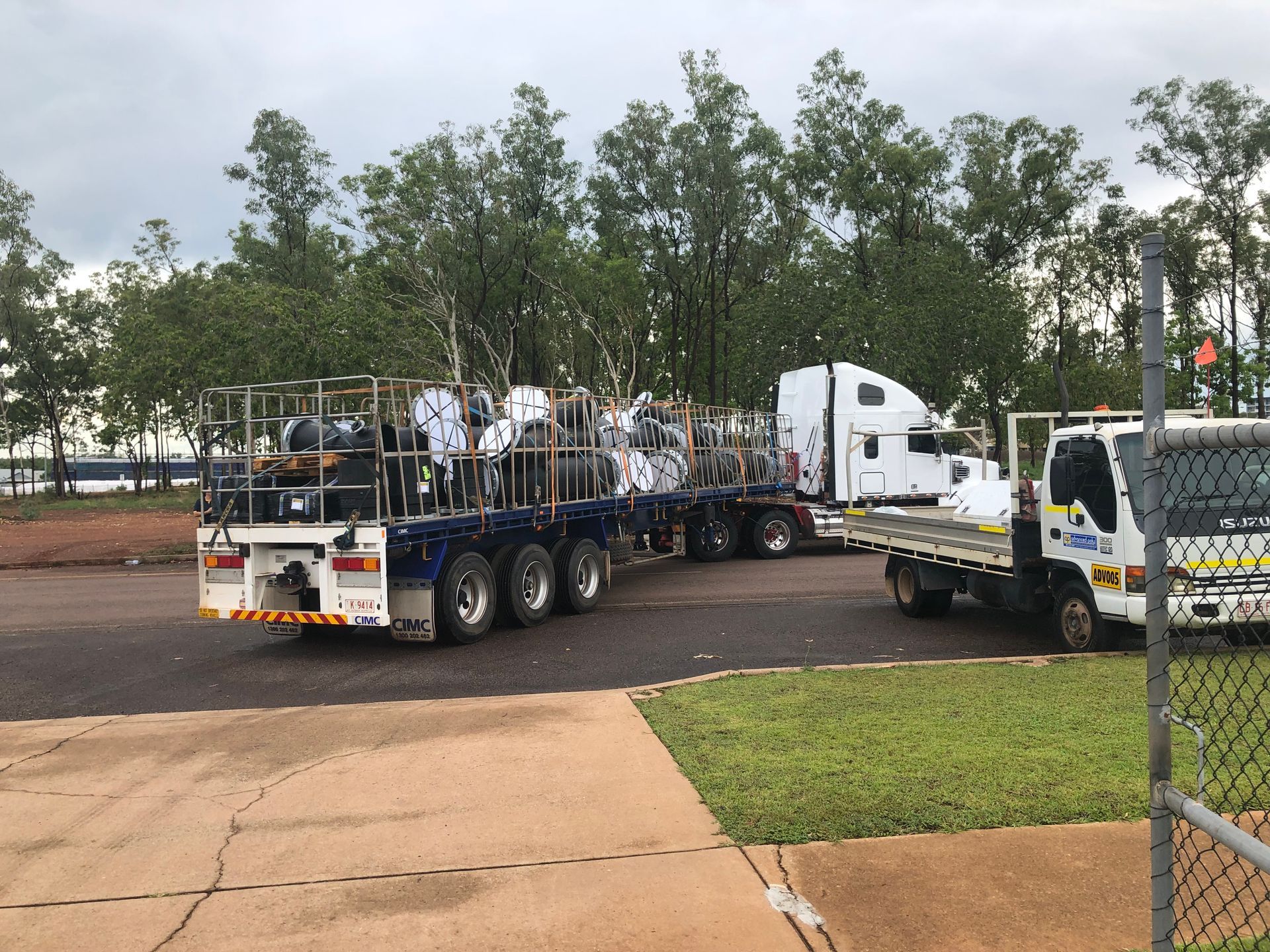 Tow truck hauling a white semi-truck on a flatbed trailer in a roadside lot — Advanced Poly in Darwin, NT 