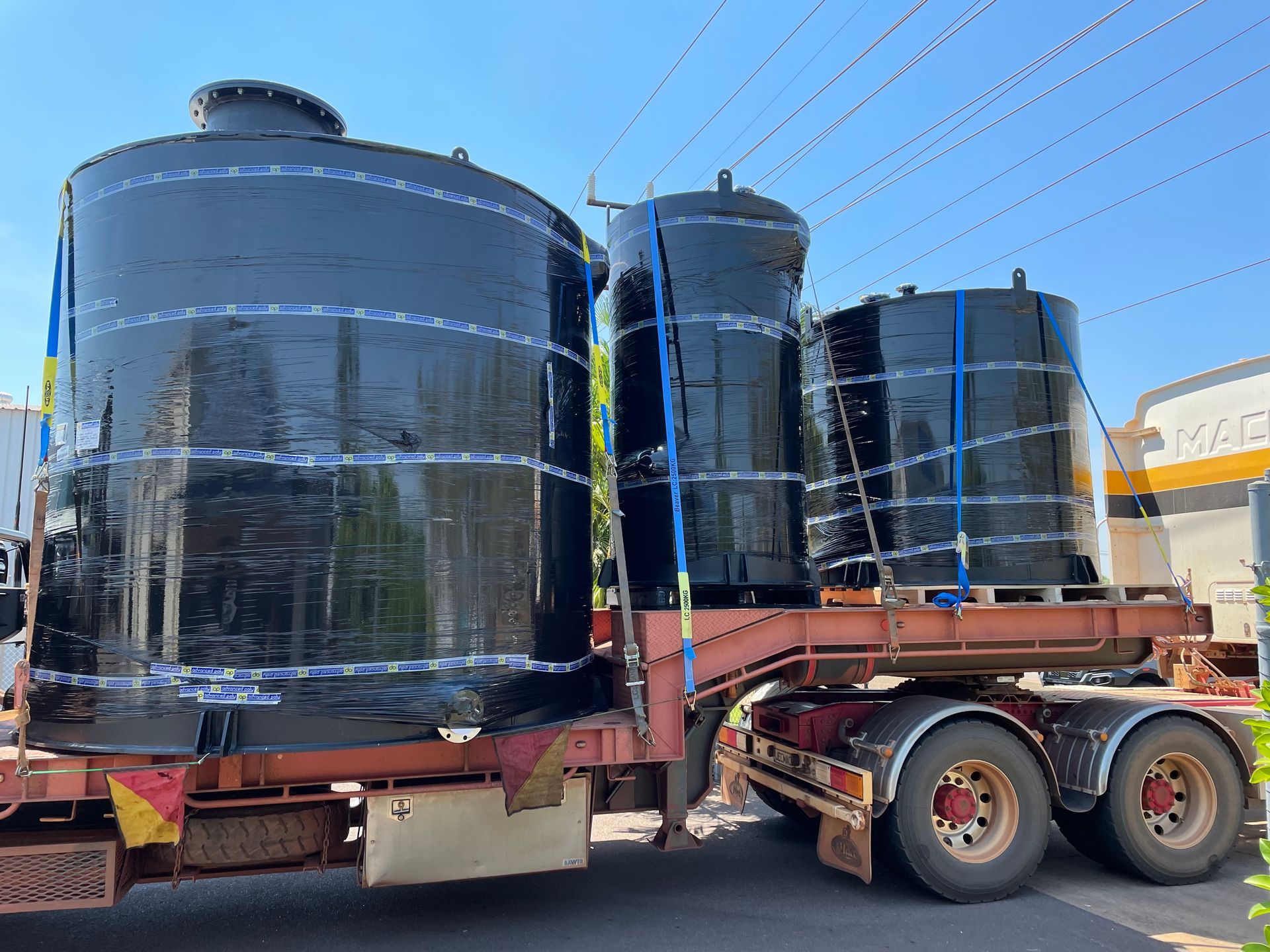 Large black industrial tanks secured on a flatbed trailer in an outdoor yard. — Advanced Poly in Darwin, NT 