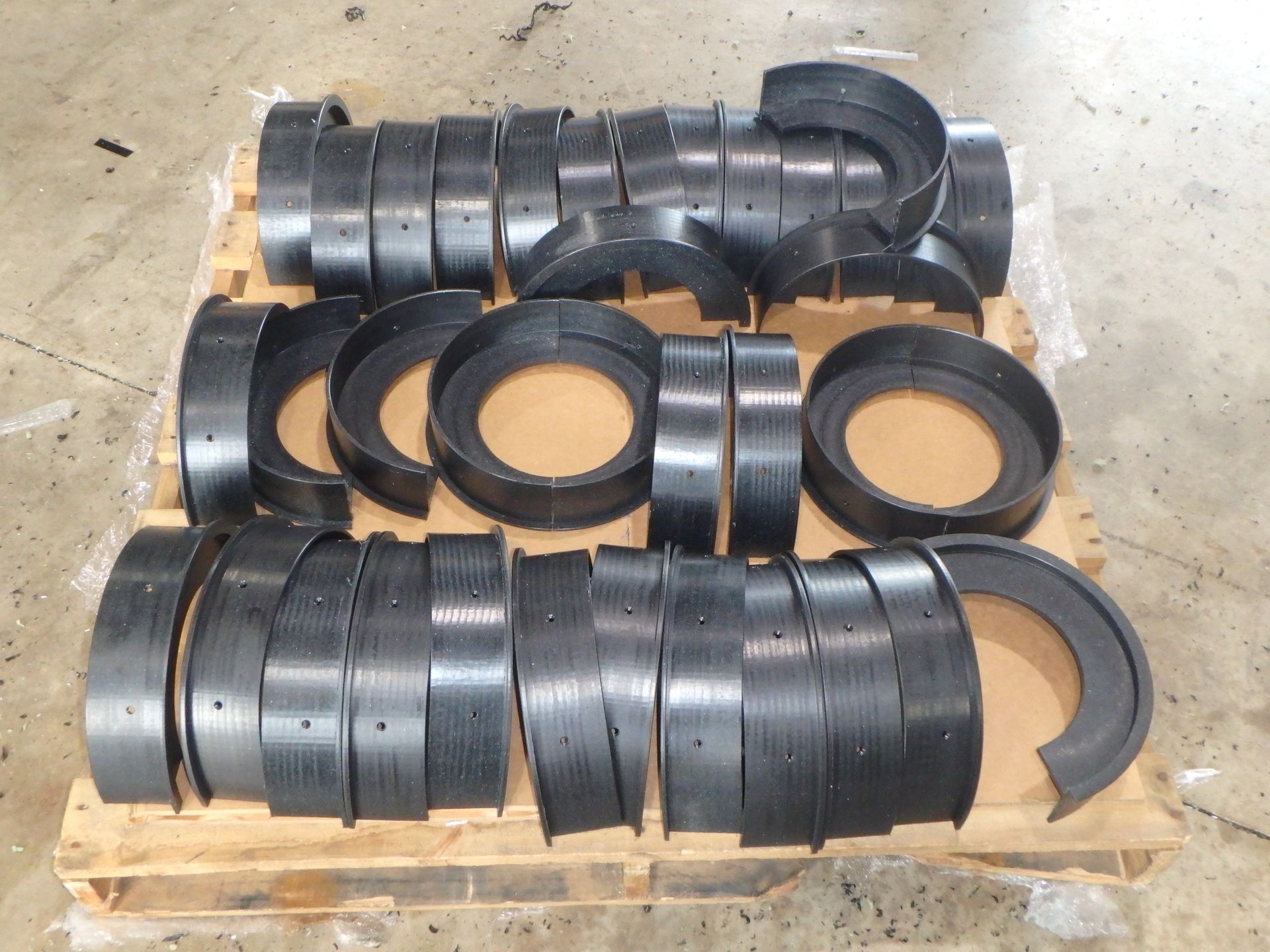 Black rubber pipe fittings and couplings stacked on a wooden pallet in a workshop. — Advanced Poly in Darwin, NT