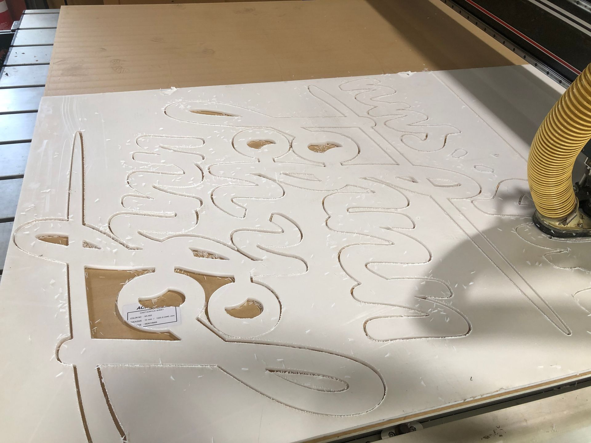 CNC router cutting a white sheet with decorative script on a worktable — Advanced Poly in Darwin, NT — Advanced Poly in Darwin, NT