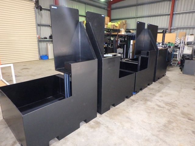 Black industrial metal equipment or carts lined up inside a warehouse workshop. — Advanced Poly in Darwin, NT